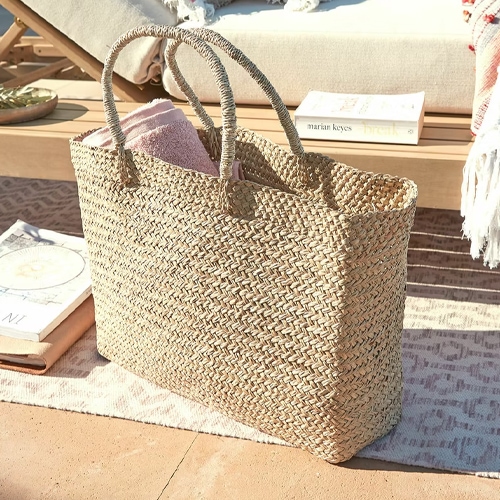 Grote gevlochten tas van zeegras in natuurlijke kleur, ideaal voor strand of boodschappen.