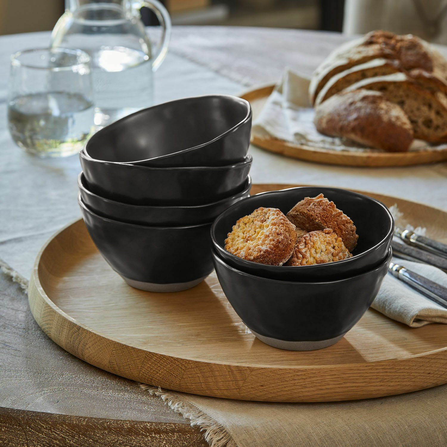 Set zwarte keramische kommen met natuurlijke bodem op houten dienblad met groene peren