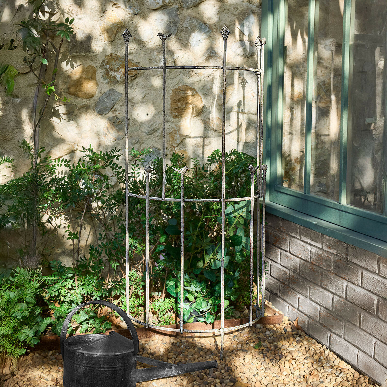 Metalen plantenbescherming met vogelmotieven in verouderde zilverkleurige tuin