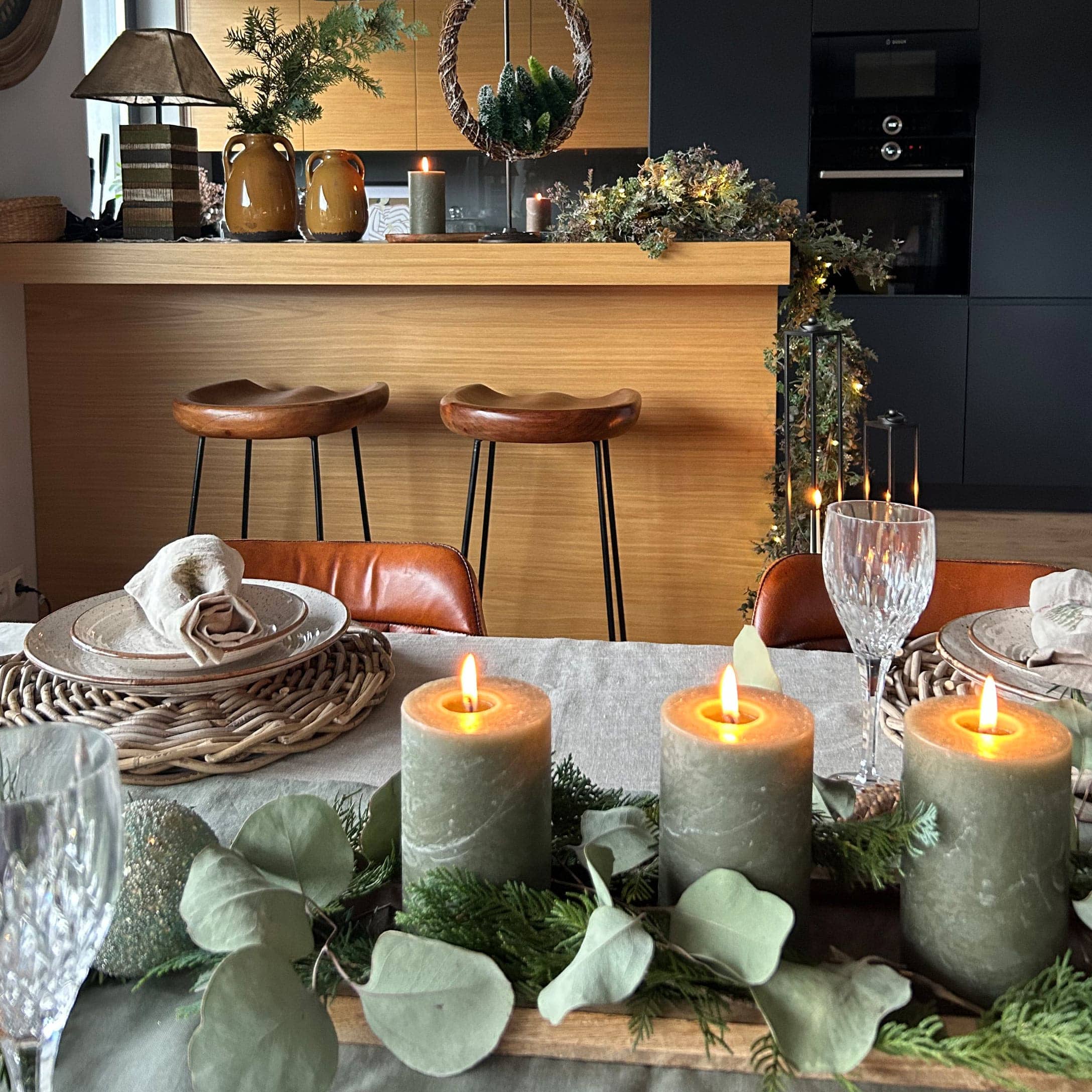 Groene decoratieve kaarsen met natuurlijke bladeren op houten dienblad op een gedekte eettafel