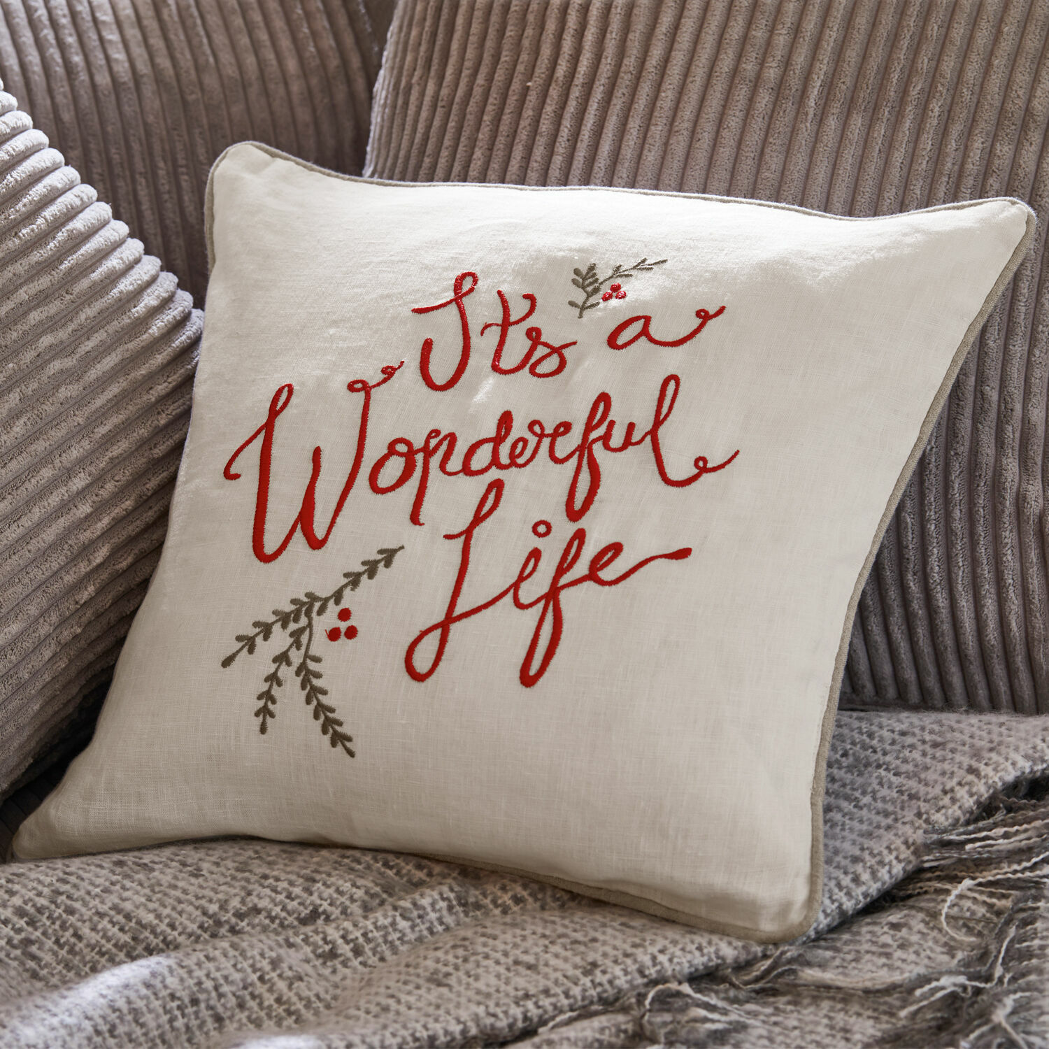 Kussenhoes Wonderful Beige linnen kussen met rode borduursel "It's a Wonderful Life" op grijze stof.