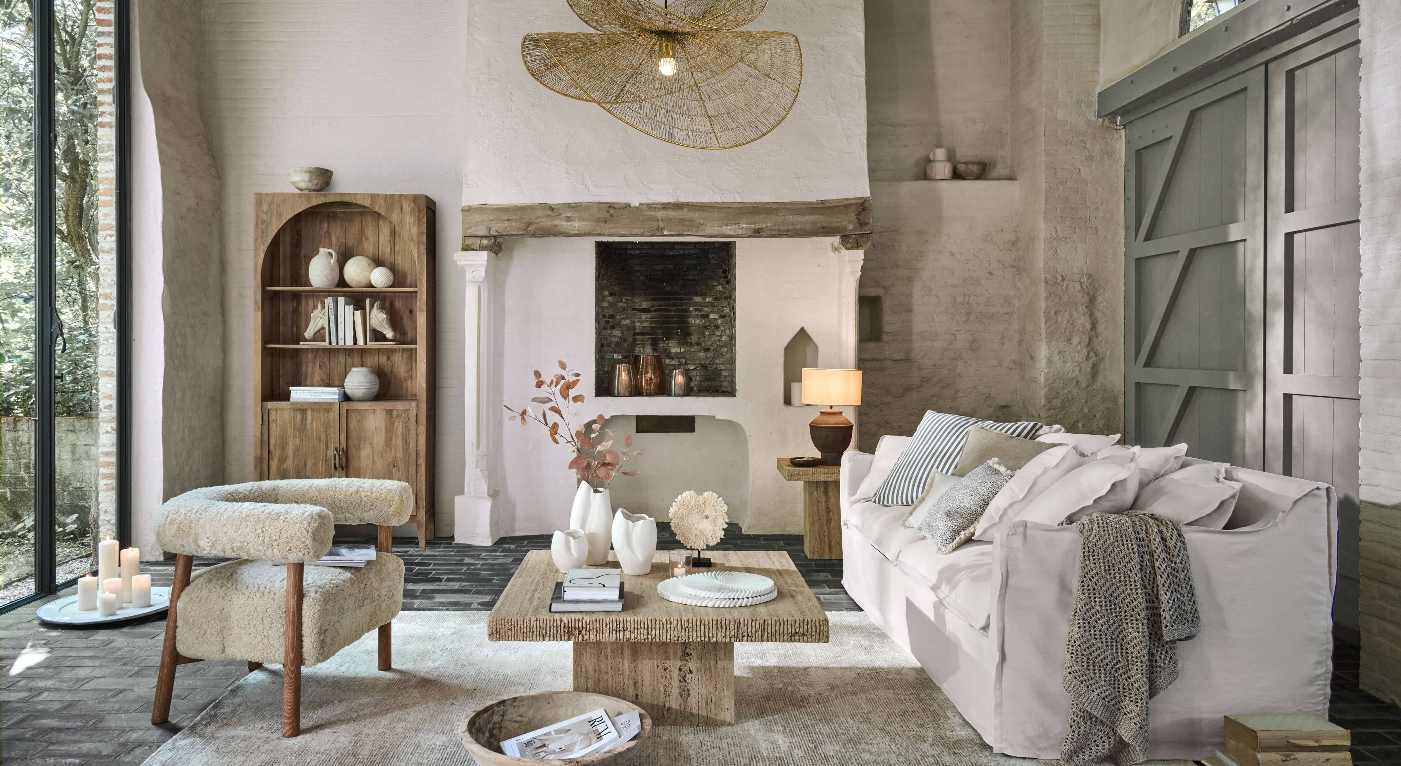 Gezellige woonkamer met witte bank, beige stoffen fauteuil en houten salontafel op lichte vloerkleed