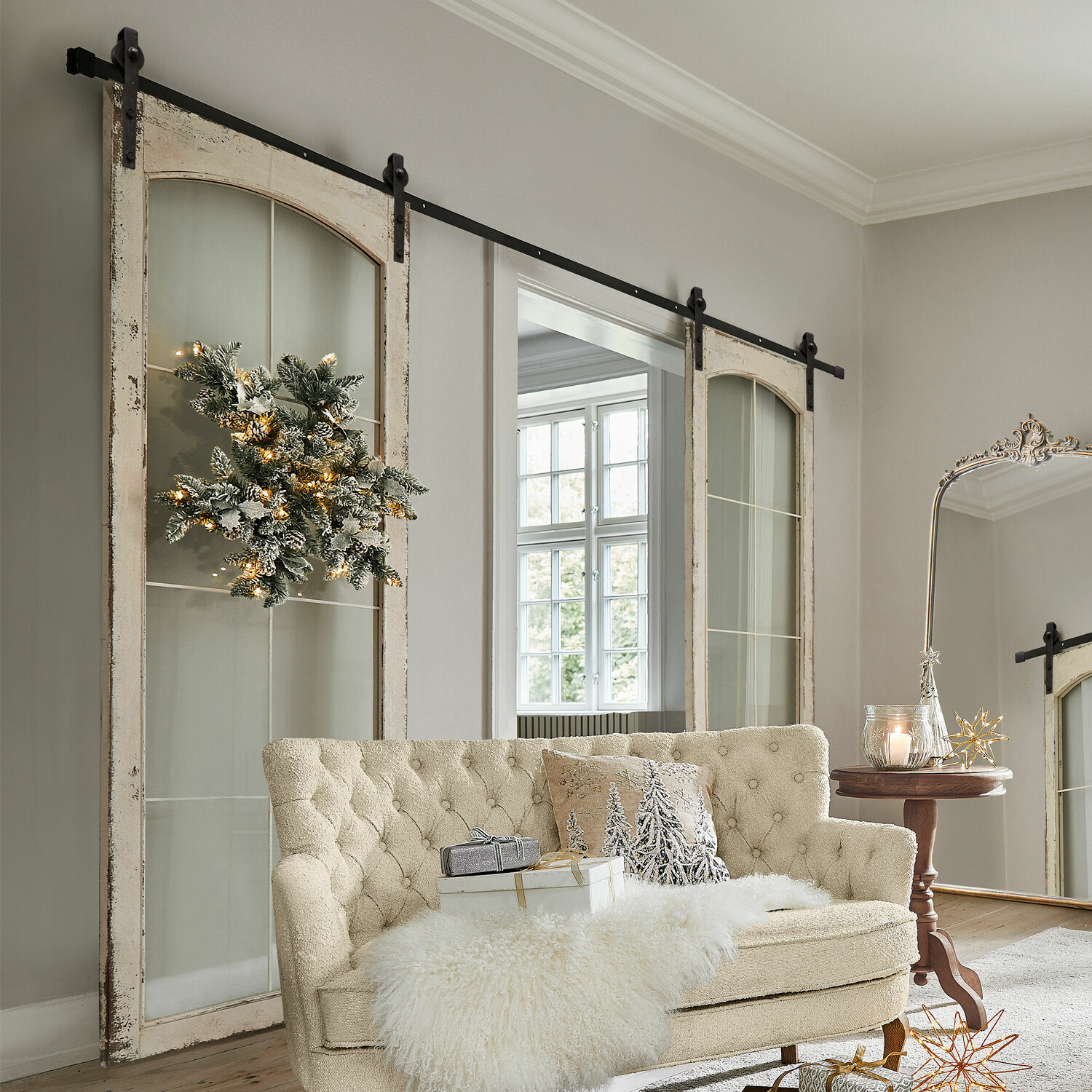 Beige gestoffeerde bank met bontdeken en kerstdecoratie in lichte woonkamer met schuifdeuren