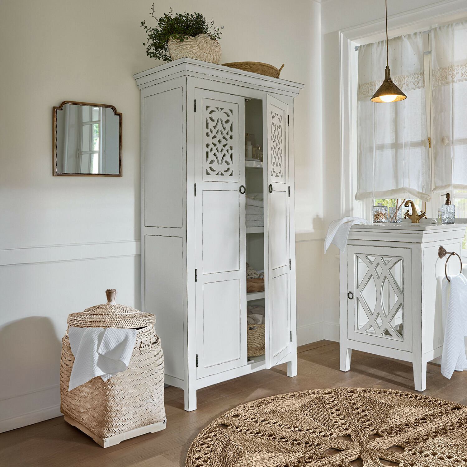 Kast Marvoux Witte houten kast met geperforeerde deuren en gevlochten rotanmand in lichte badkamer