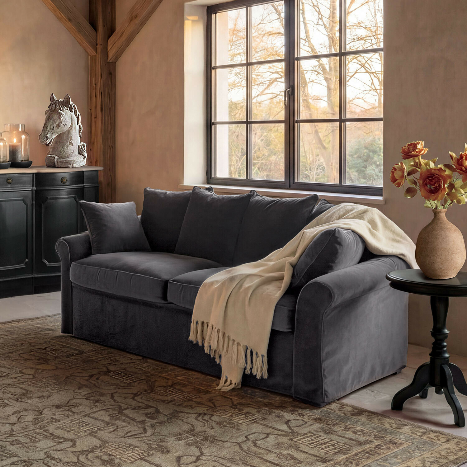 Bank Long Beach Grijze fluwelen bank met crème deken in gezellige woonkamer met paardenhoofddecoratie en bloemen
