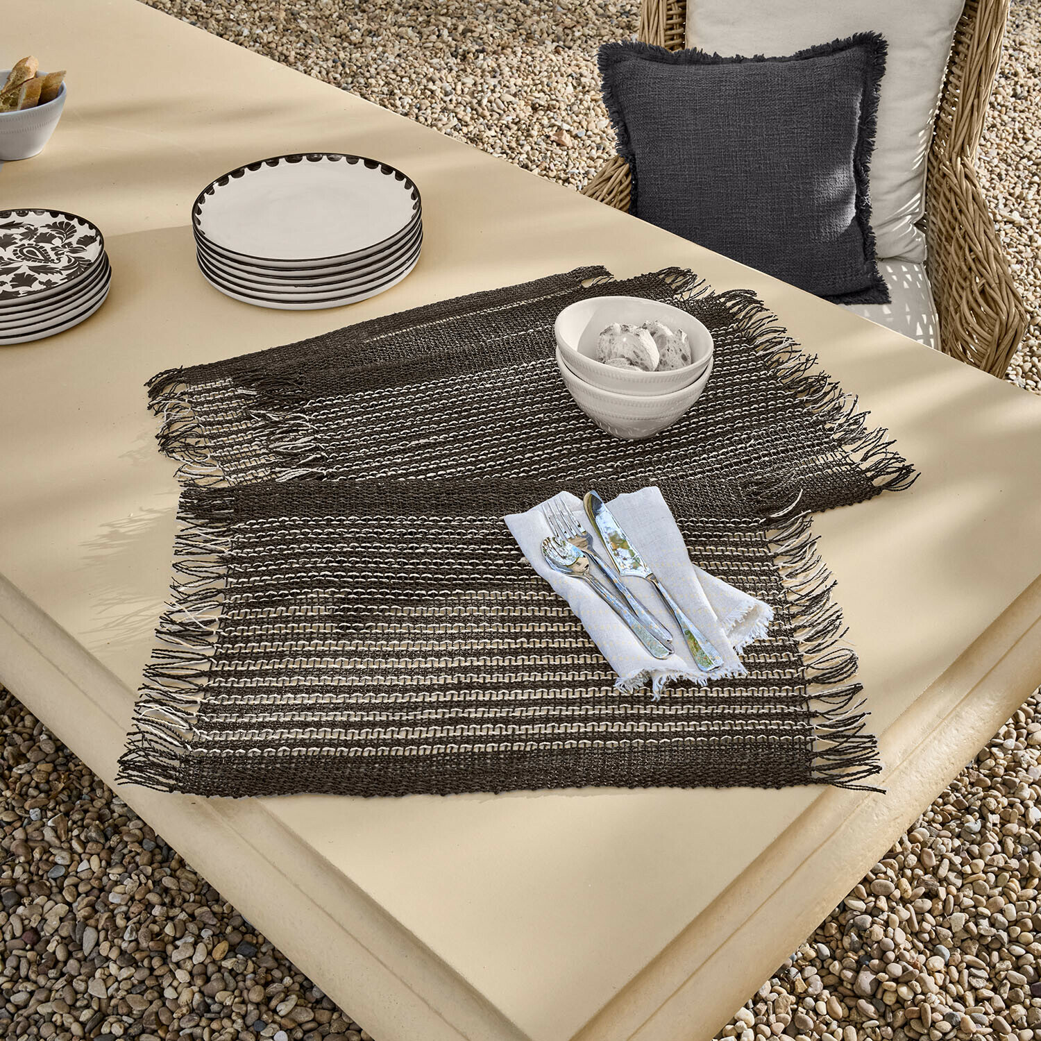 Bruine geweven placemats met franjes op beige tafel met servies en bestek