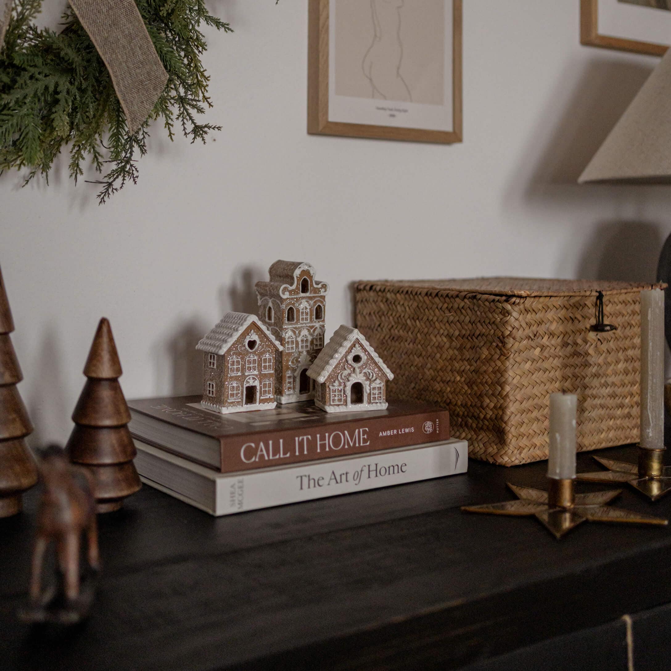 Decoratieve kleihuisjes op boeken op een donkere tafel met natuurlijke accessoires en kaarsen