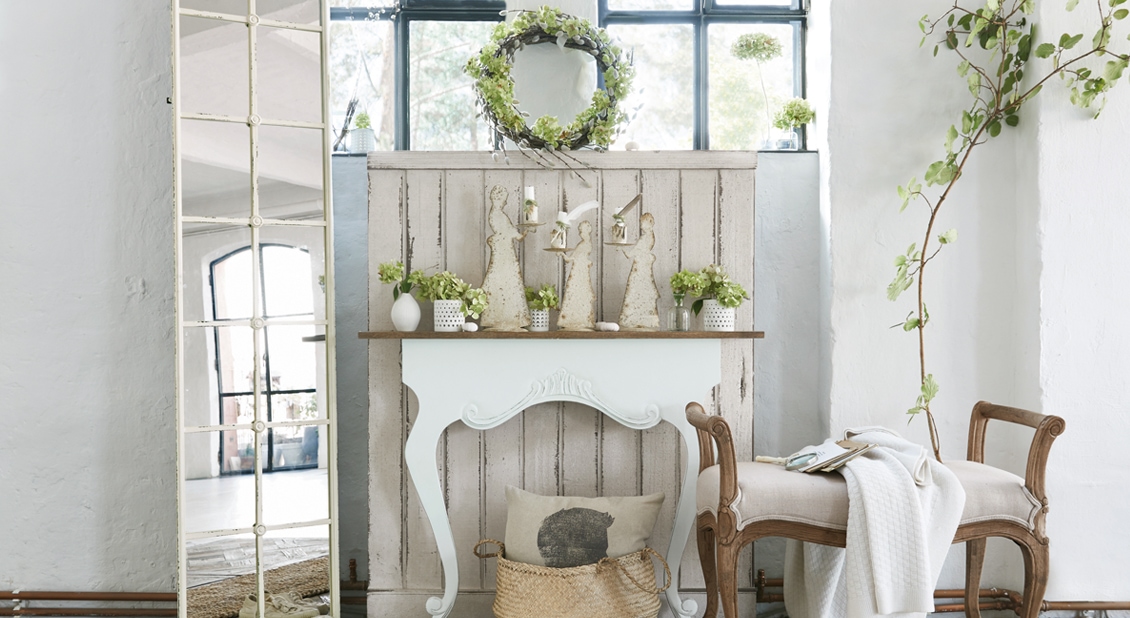 Witte sidetable met decoraties en groene planten in lichte, rustieke ruimte