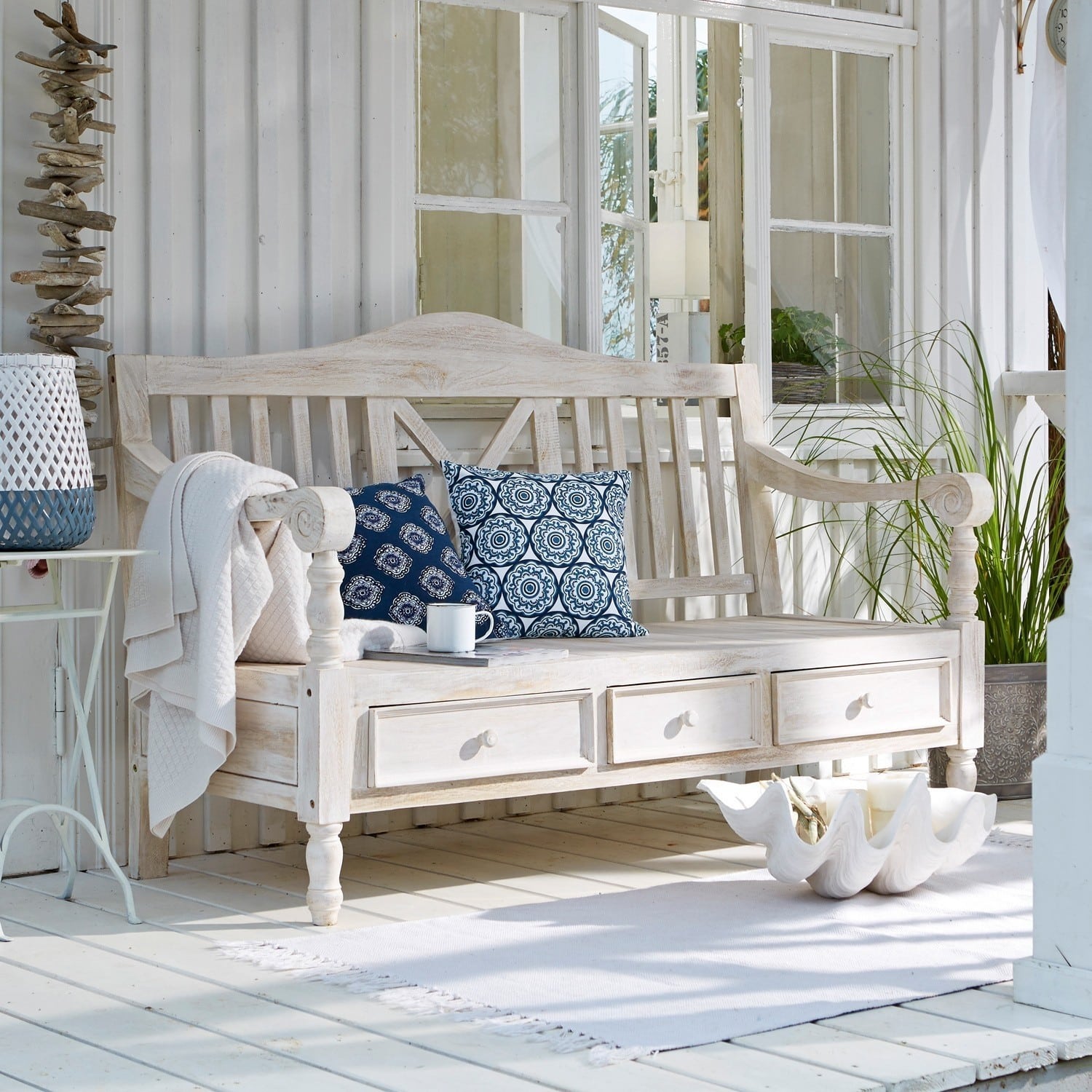 Witte houten bank met drie lades en blauwe kussens in vintage stijl