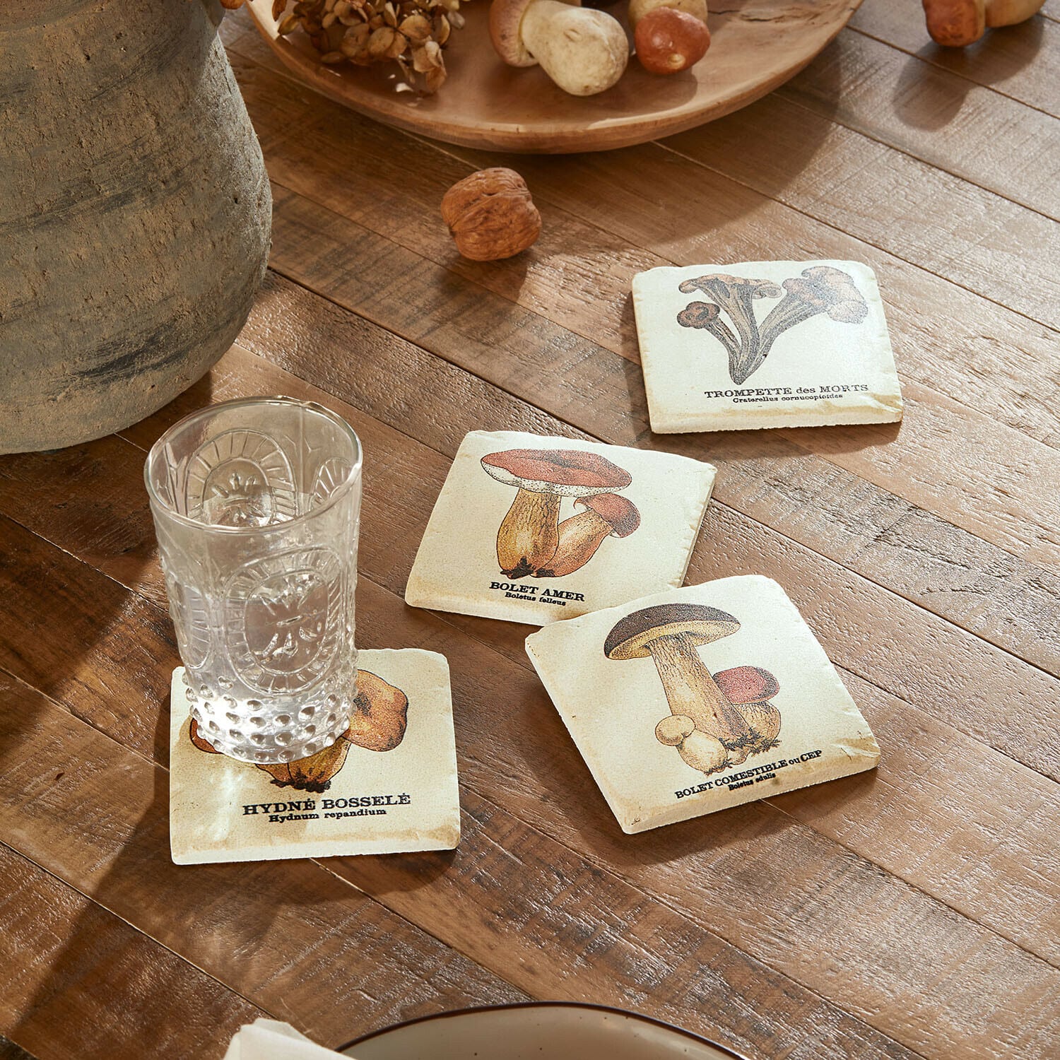 Onderzetter set van 4 Jandoria Onderzetters met paddenstoelillustraties op houten tafel met helder glas en noten