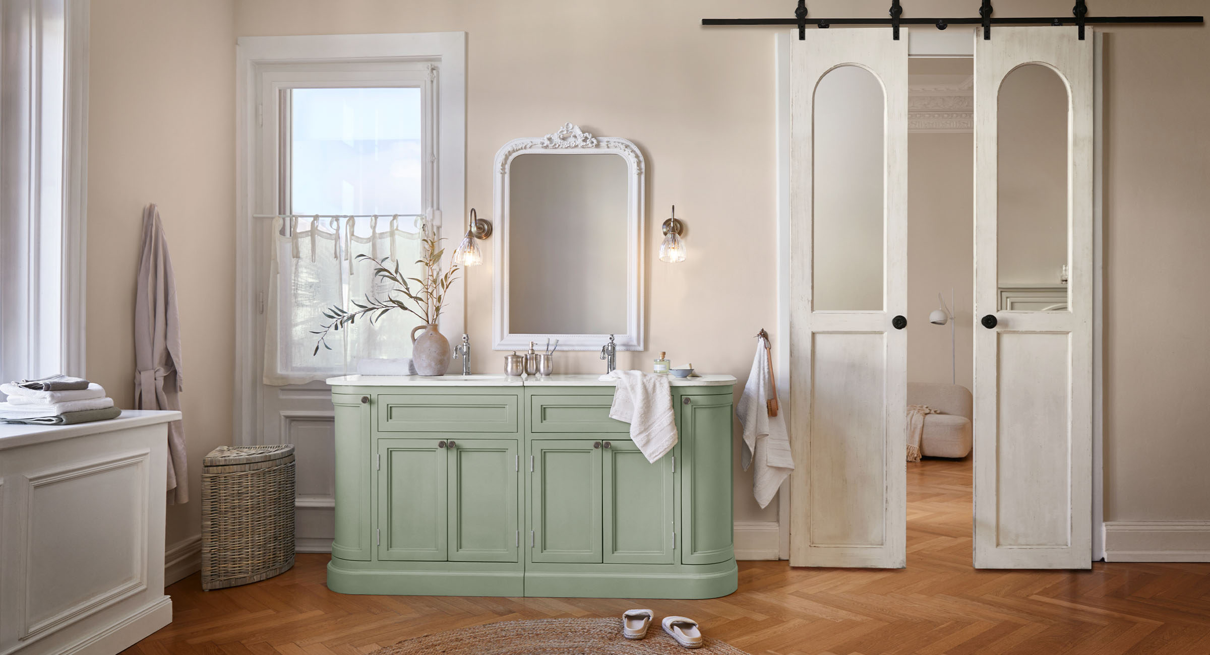 Badkamer met groene houten kast, witte spiegelrand en lichte muren in vintage stijl