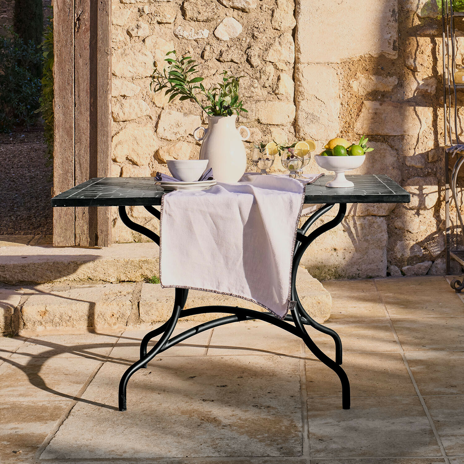 Tafel Maurelle Tuin tafel met zwart metalen frame en marmeren blad, versierd met witte vaas en fruit