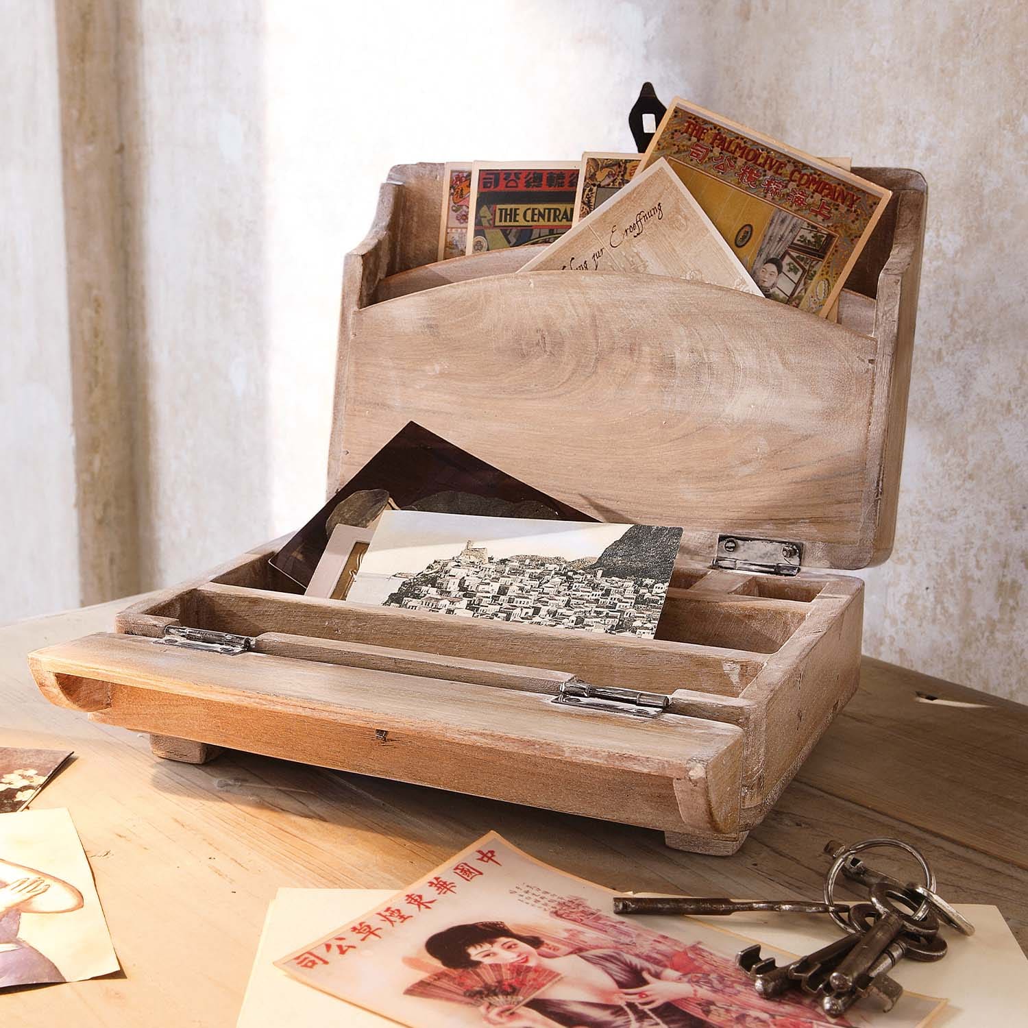 Houten brievenbus in natuurlijke kleur met vintage ansichtkaarten en metalen sleutels op houten tafel