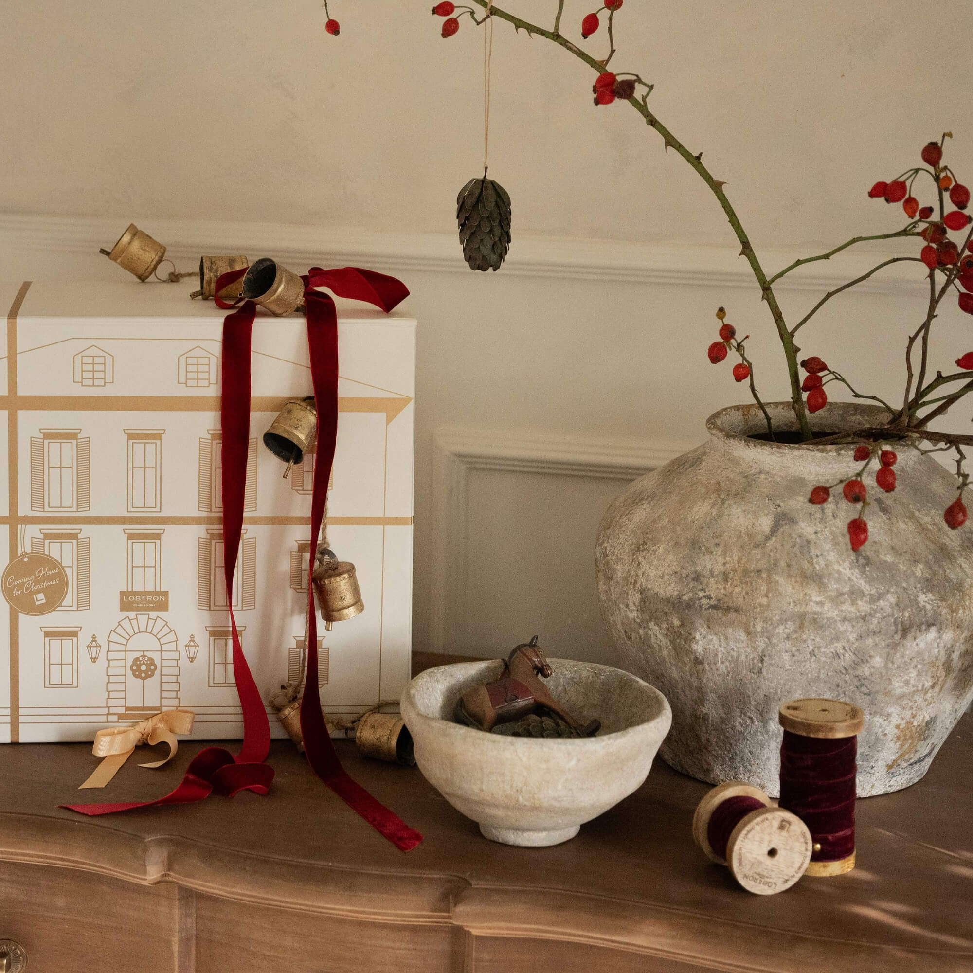 Kerstdecoratie met rode linten, bellen en keramische kom op houten tafel