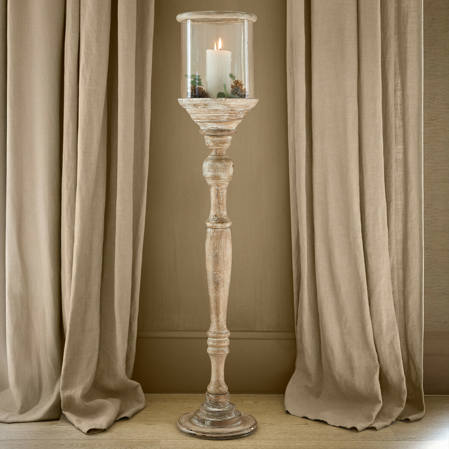 Stijlvolle houten fauteuil met groene kussens in lichte, natuurlijke ruimte met decoratieve lantaarn