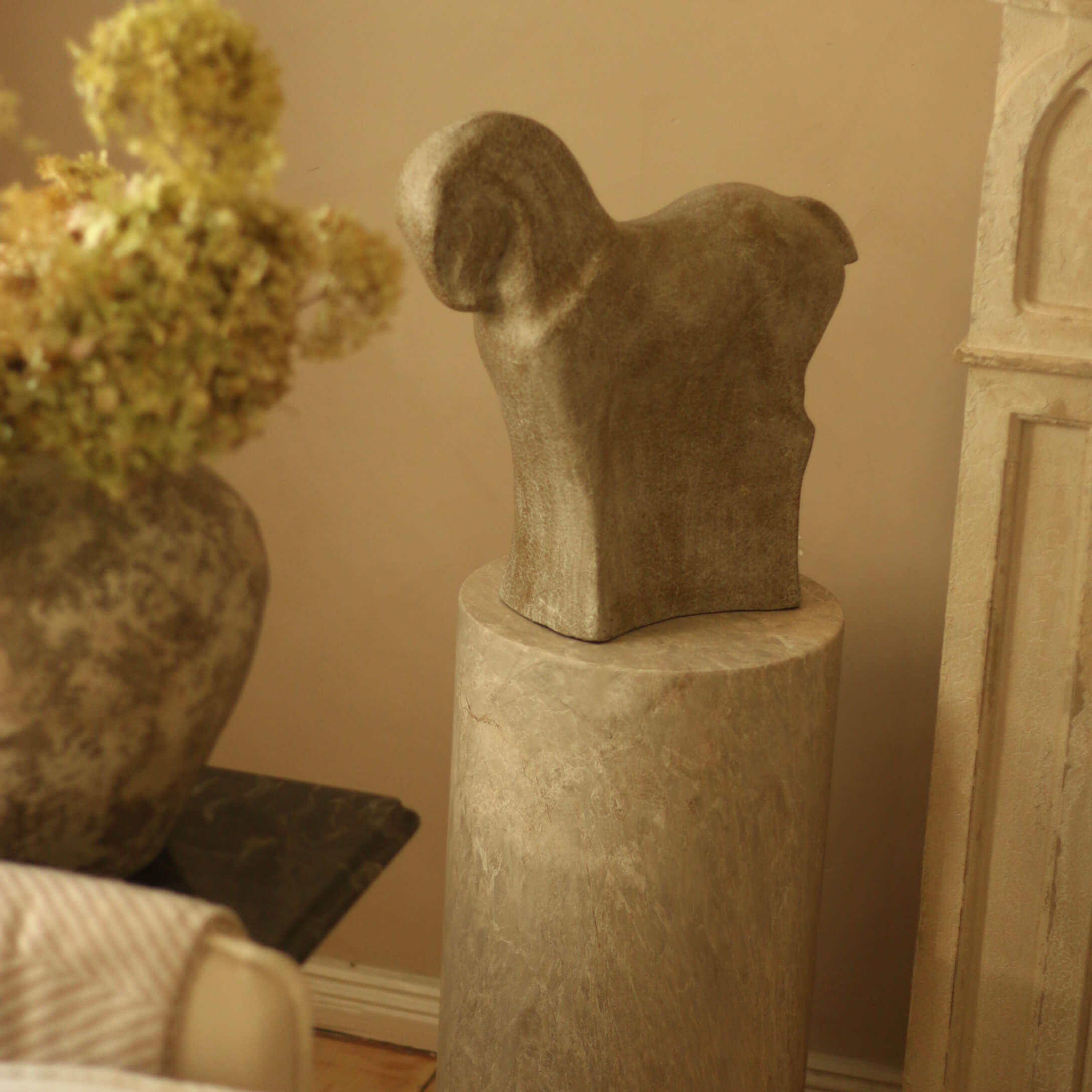 Steenbeeld in dierenvorm op marmeren sokkel in warme interieursetting