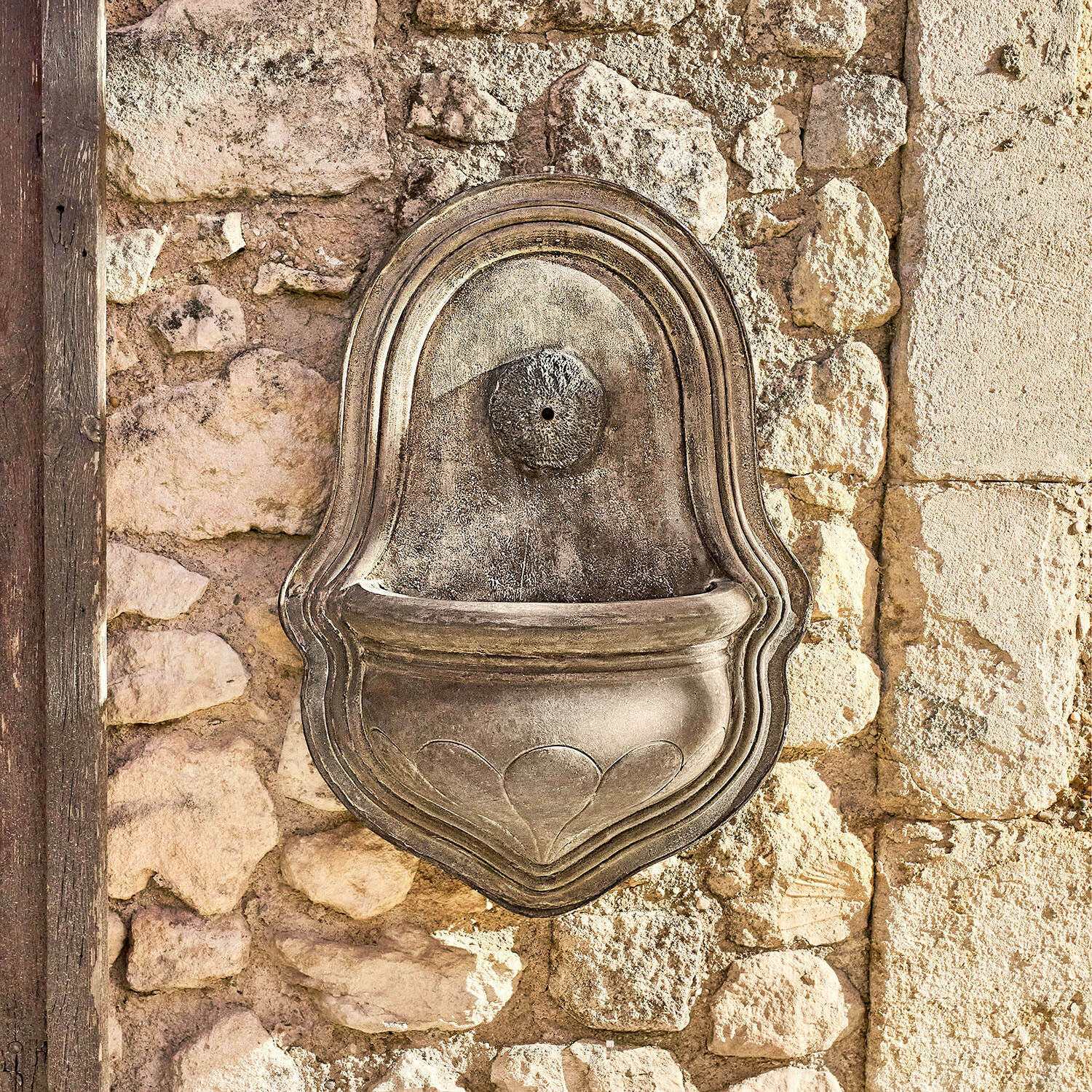 Wandfontein Veliras Decoratieve grijze stenen wandfontein gemonteerd op een stenen muur, buiten tuinornament