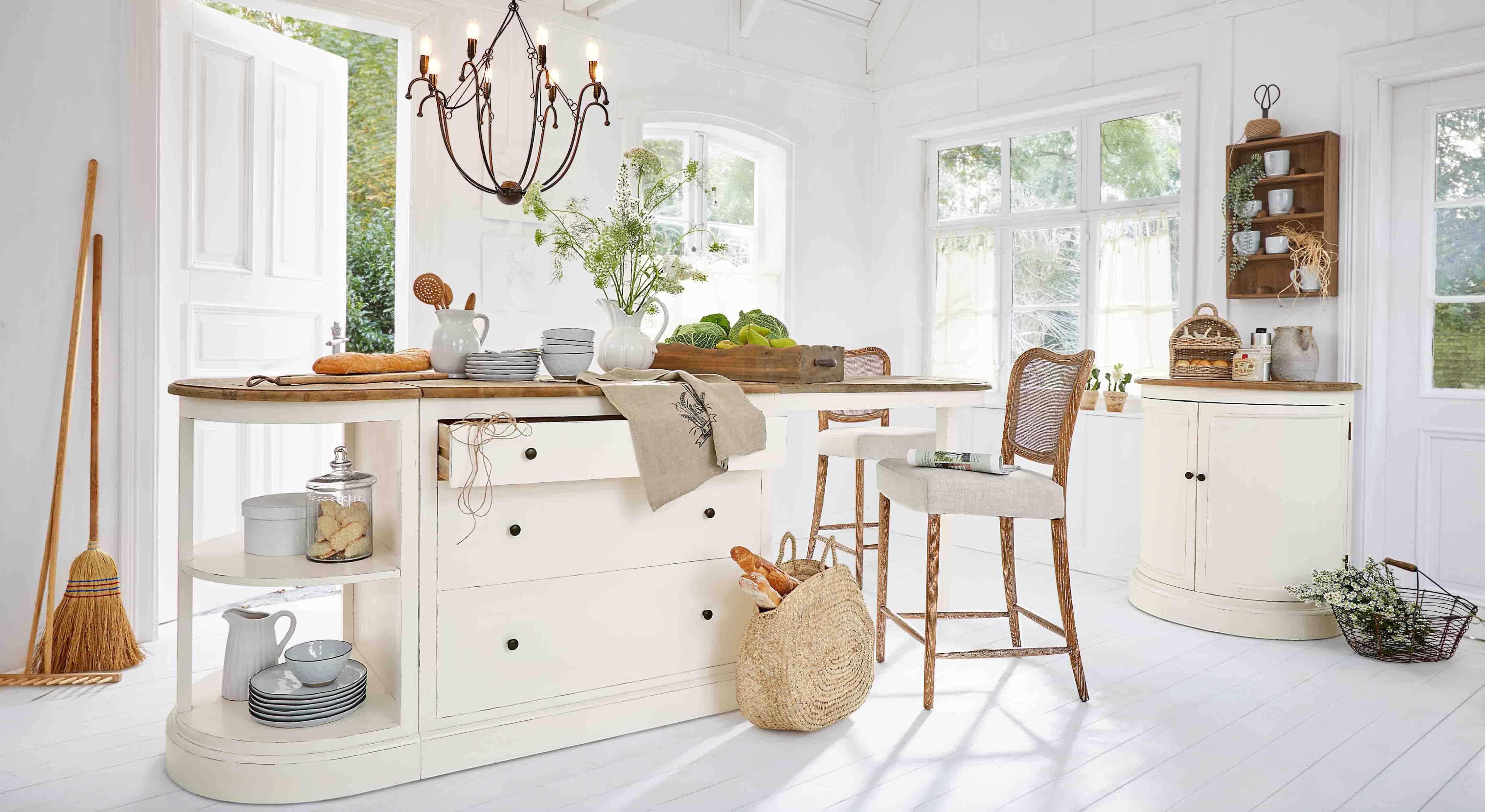 Rustieke keuken met wit eiland en houten werkblad, natuurlijke decoraties en daglicht