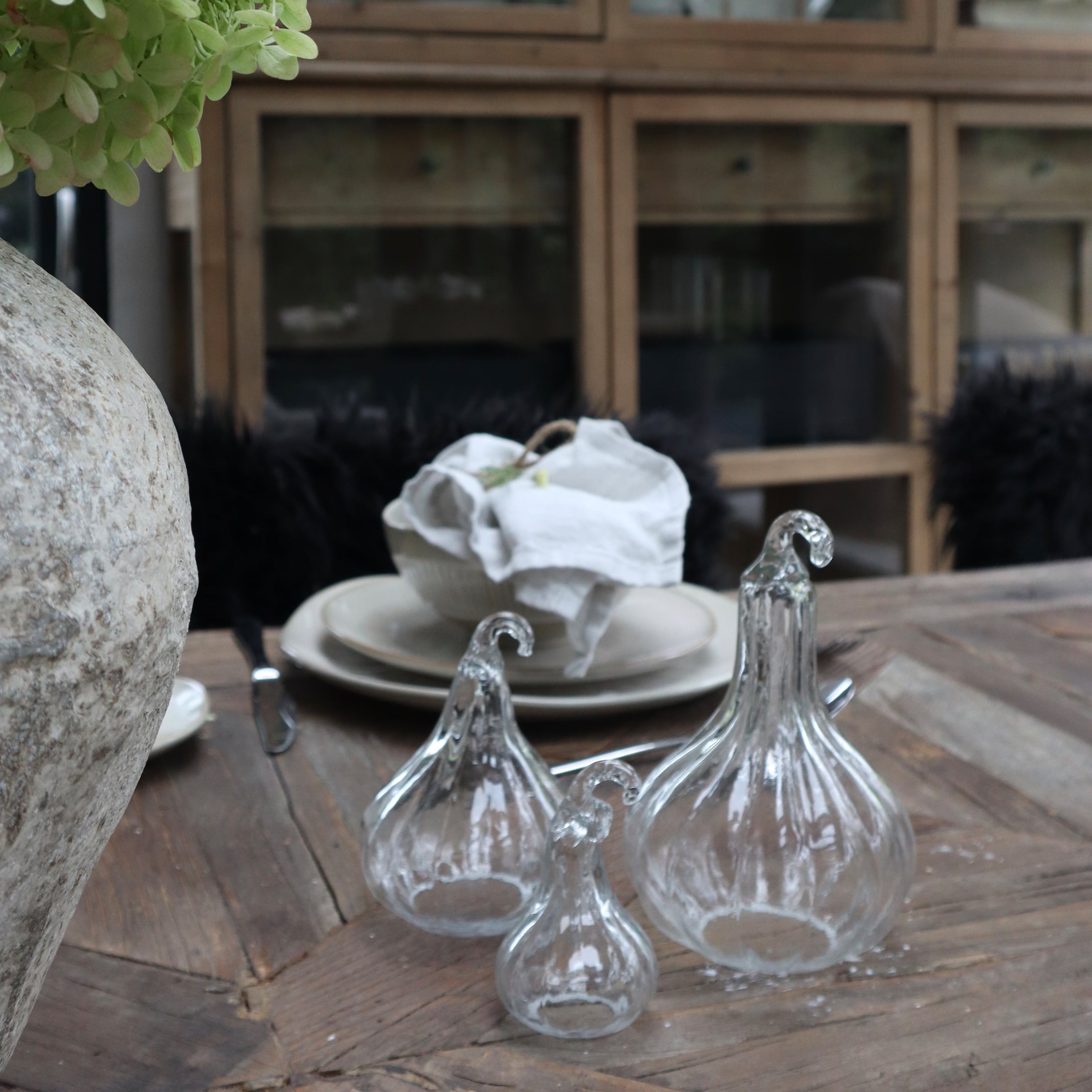 Transparante glazen decoraties in peer vorm op houten tafel in rustieke omgeving