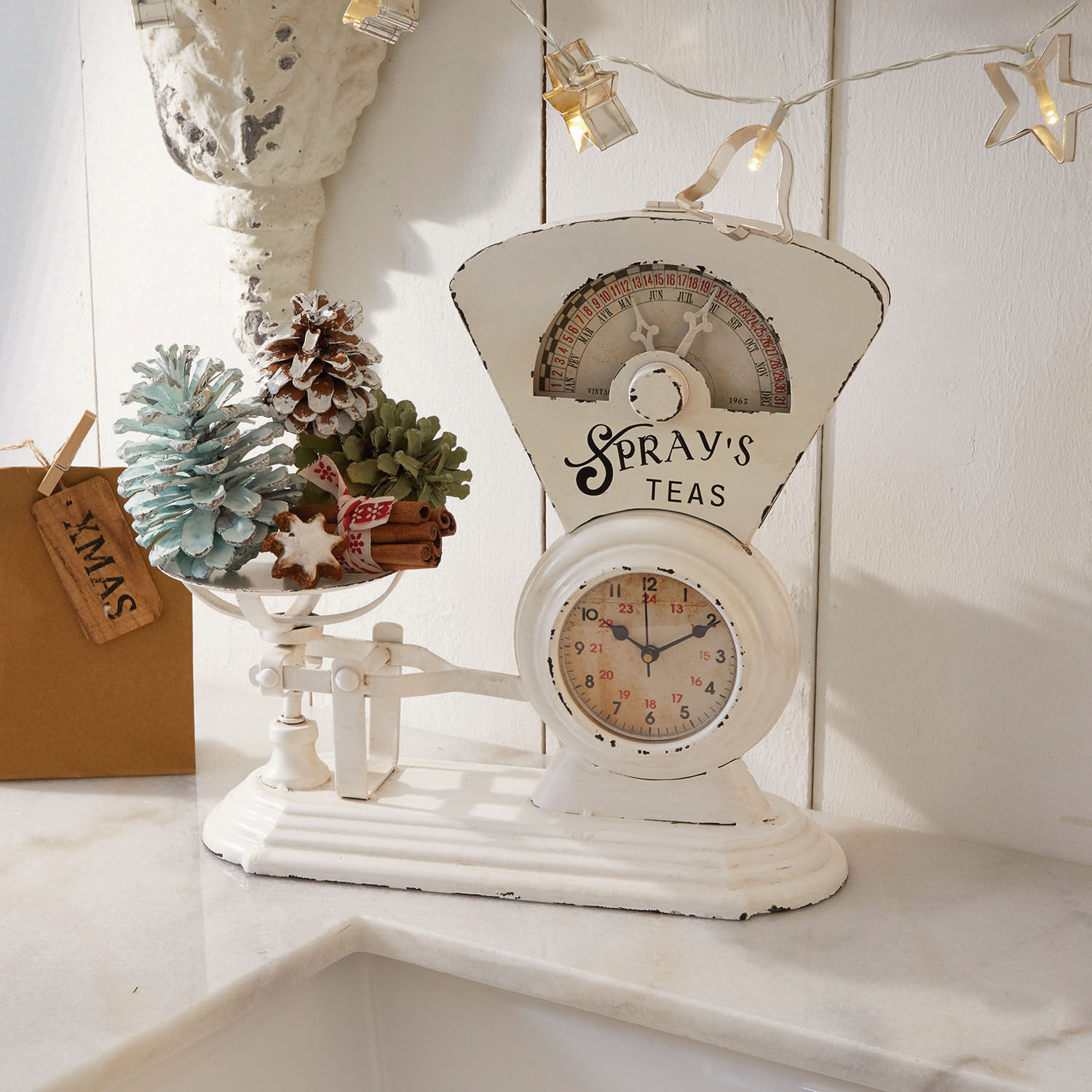 Klok Balances Witte metalen keukenweegschaal met kerstdecoraties en dennenappels op het aanrecht