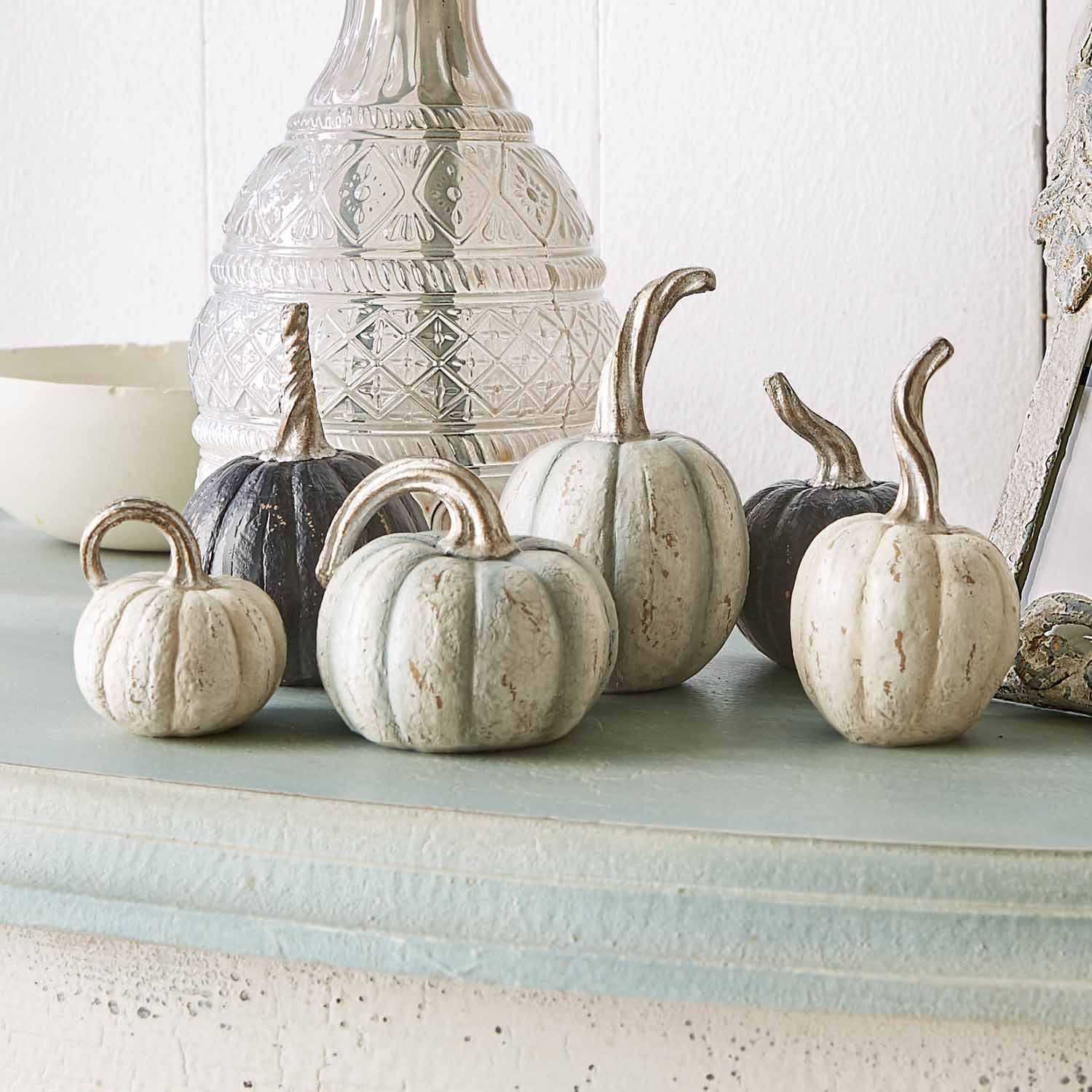 Decoratieve metalen pompoenen in wit en zwart op lichte plank voor herfstdecoratie