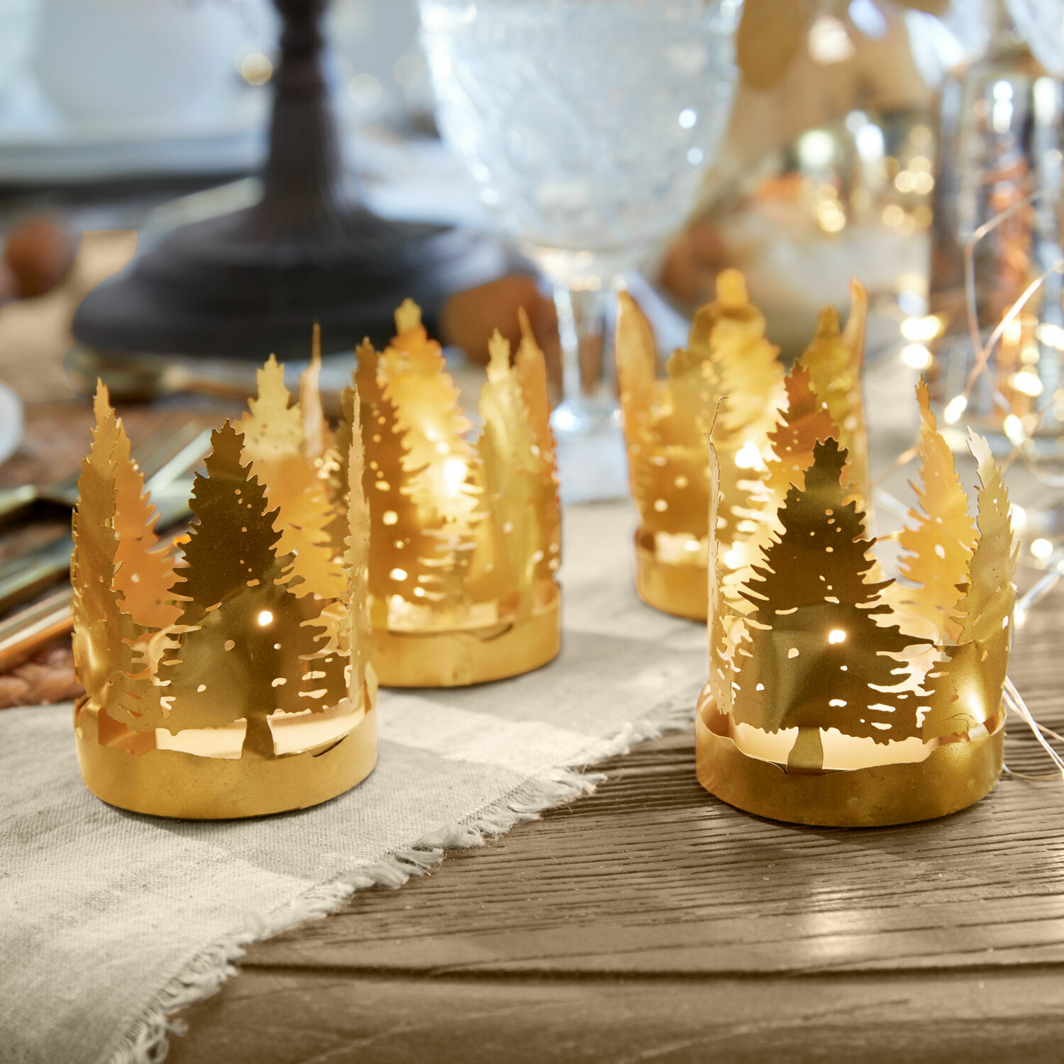 Theelichtjeshouder set van 4 Ismerie Gouden metalen theelichthouders met kerstboommotief op houten tafel, feestelijke decoratie