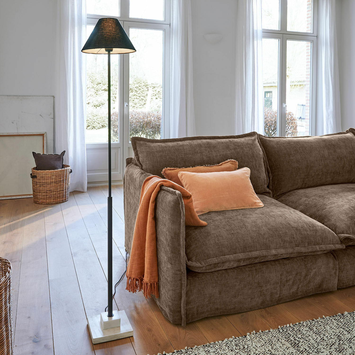 Staande lamp met zwarte kap en marmeren voet in lichte woonkamer met bruine bank