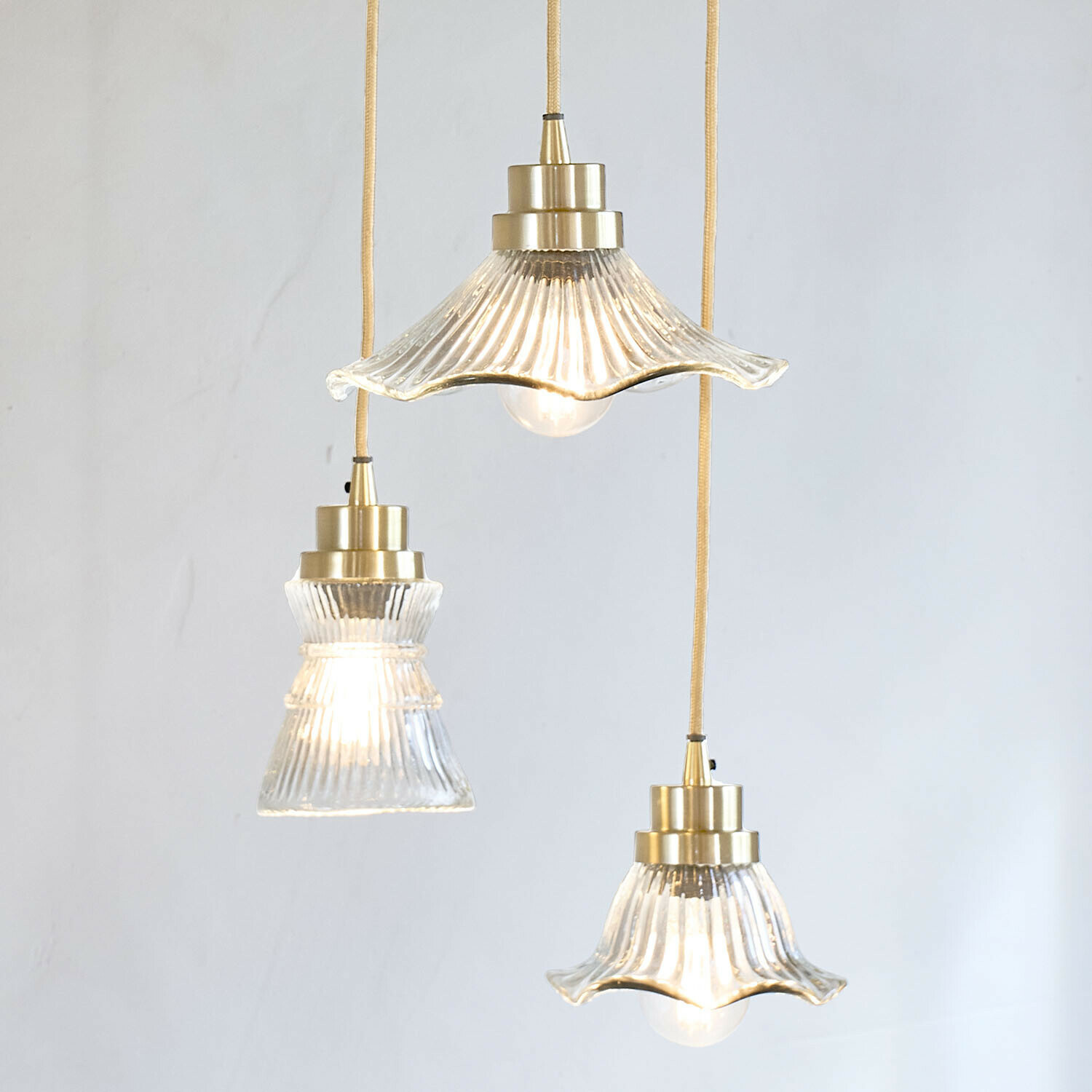 Set van drie glazen hanglampen met messing details en gele kabel voor sfeervolle binnenverlichting