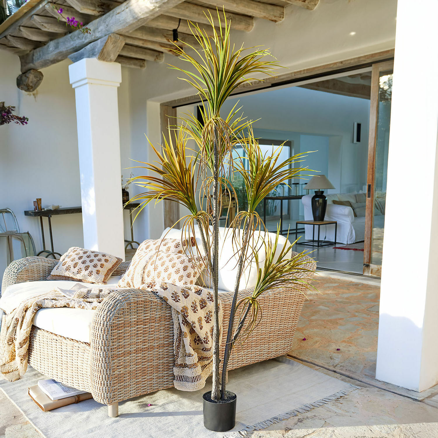 Decoratieve potplant Ancerac Kunstplant in zwarte pot op terras met rotan bank en lichte deken