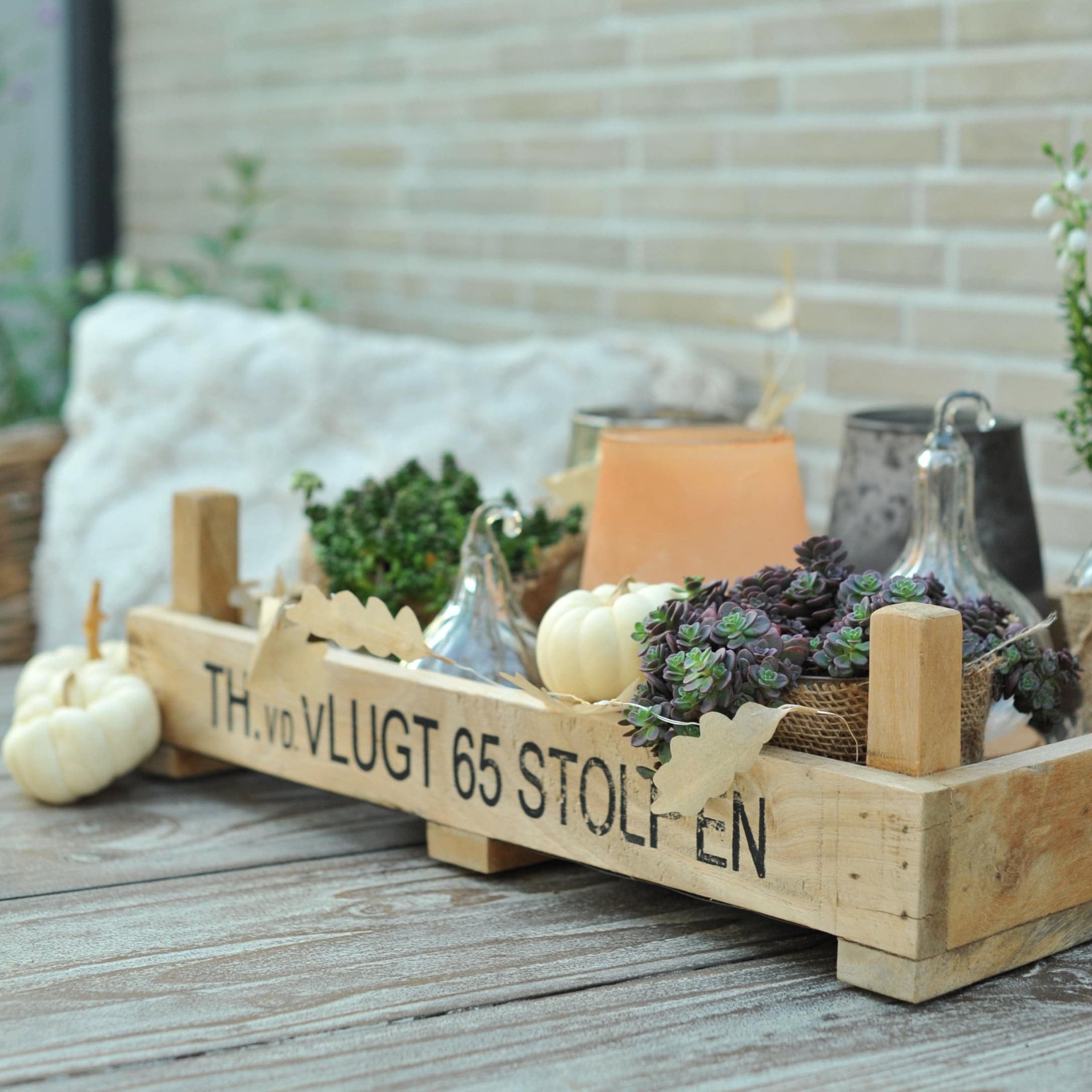 Houten dienblad met vetplanten, witte pompoenen en kaarsen voor herfstdecoratie binnenshuis