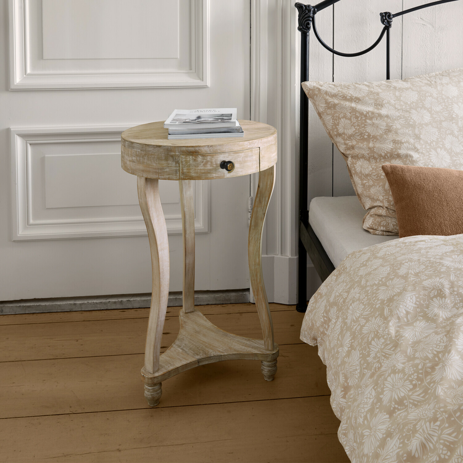 Bijzettafel Elmbury Ronde nachtkast van licht hout met lade naast bed met beige bloemenbeddegoed