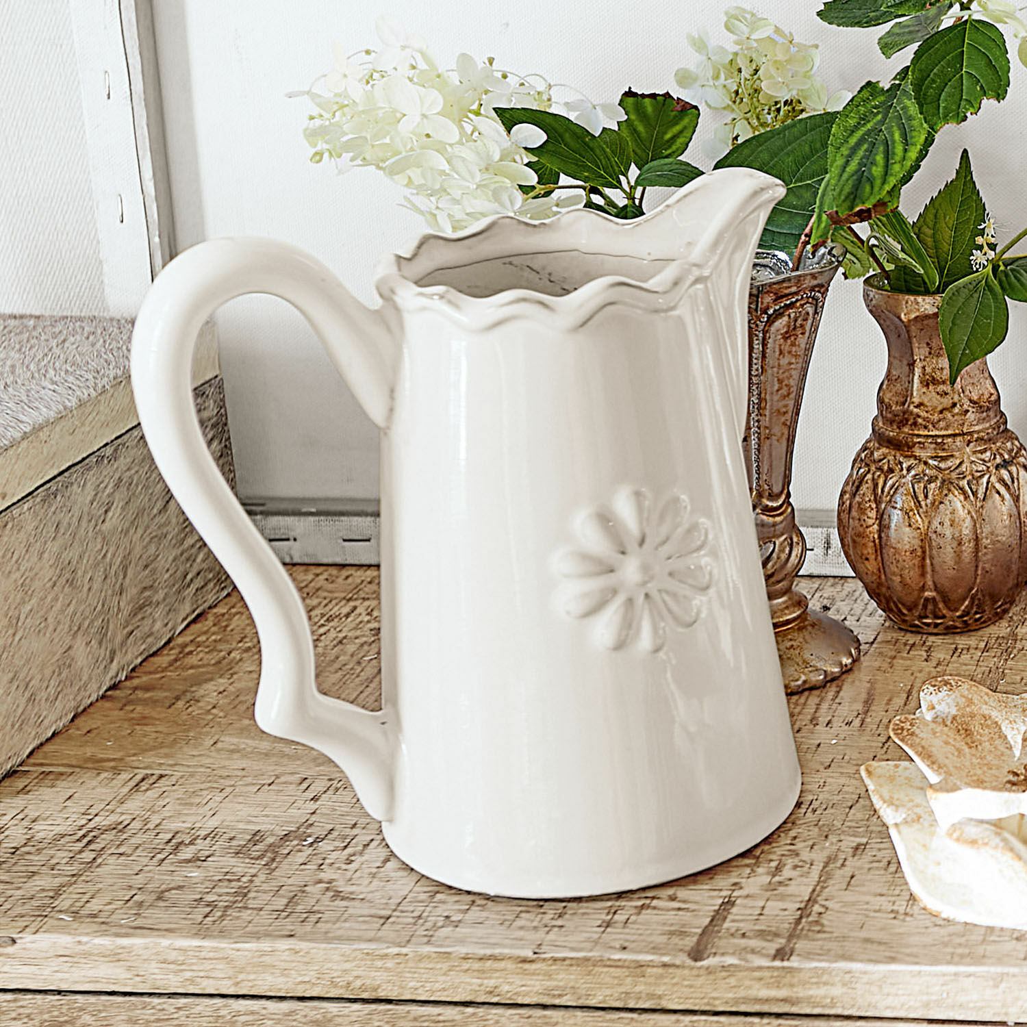 Witte keramische kan met bloemmotief op houten tafel, interieurdecoratie