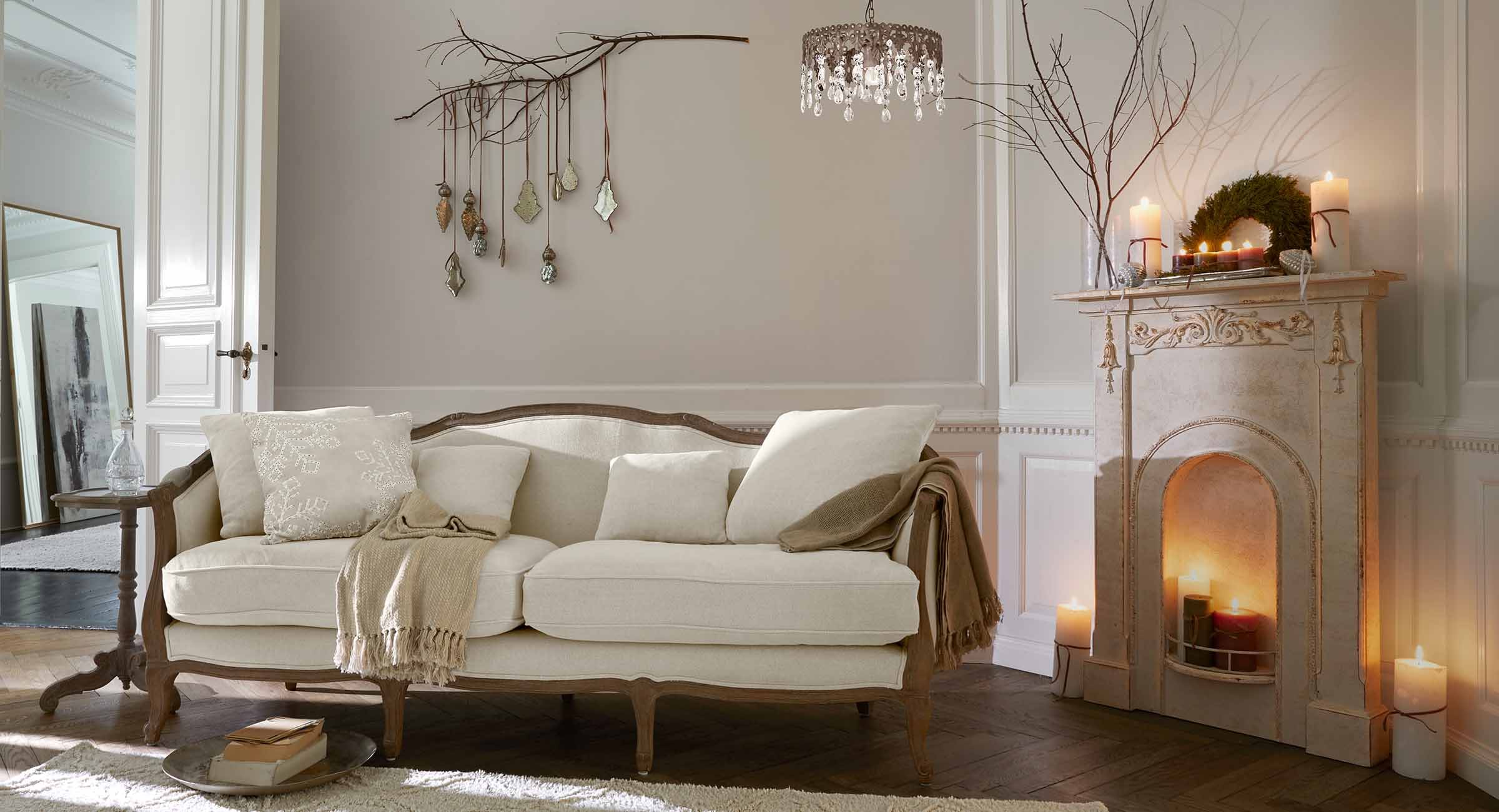 Beige bank met houten frame in klassieke woonkamer met open haard en wanddecoraties