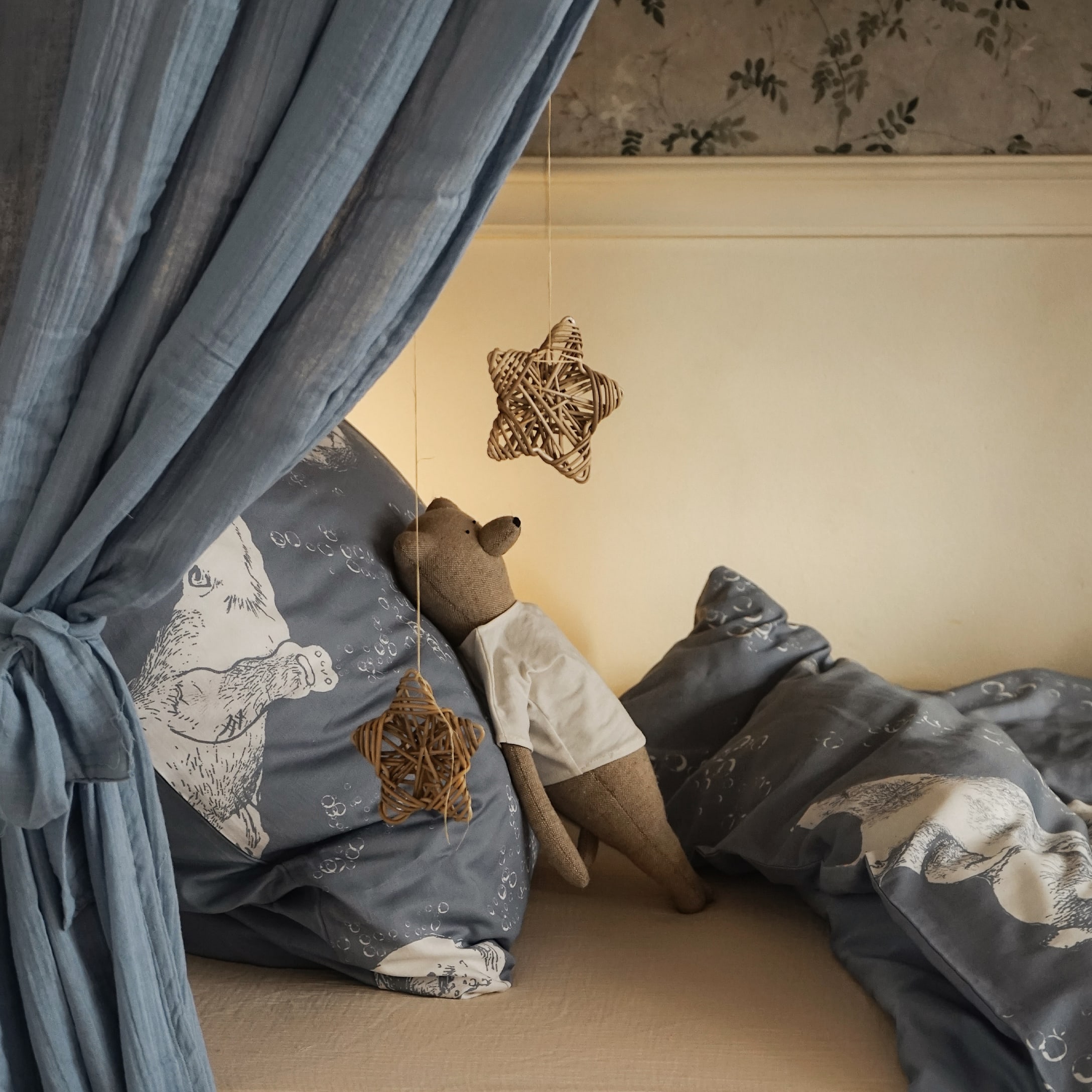 Gezellig bed met blauw beddengoed met berenmotief en bruine teddybeer met wit shirt