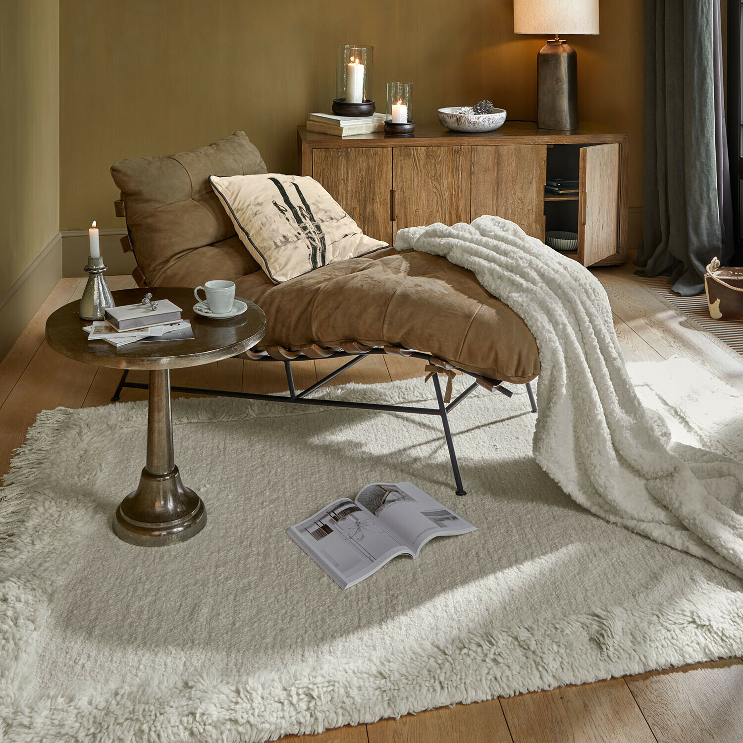 Bruine leren fauteuil met witte deken op crèmekleurig tapijt in gezellige woonkamer