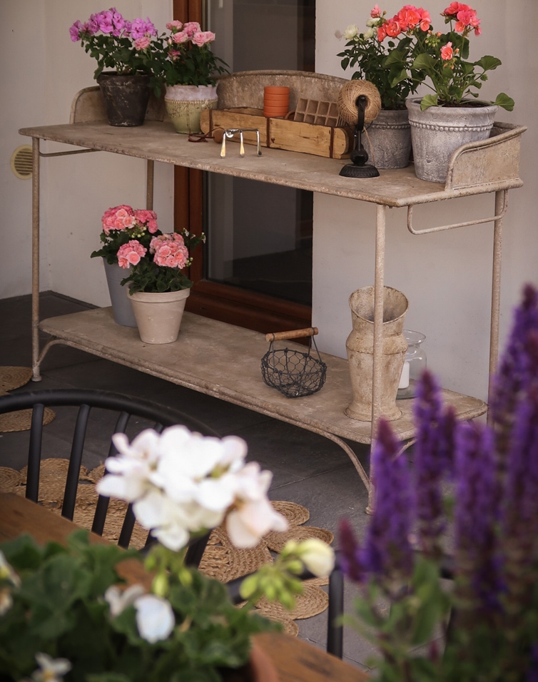 Metalen tuintafel met bloempotten en decoraties op terras, natuurlijke kleur