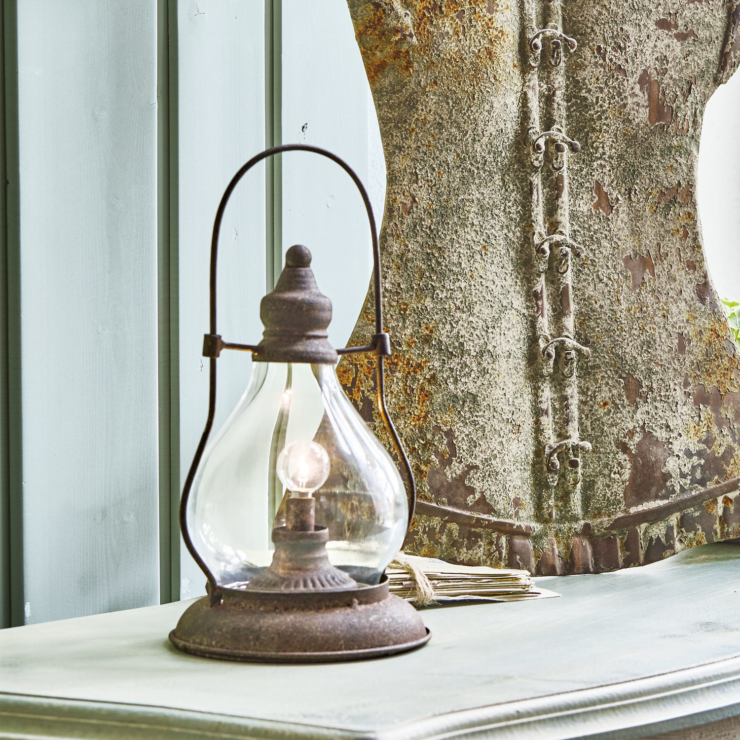 Rustieke tafellamp van roestig metaal op lichte houten tafel in vintage stijl