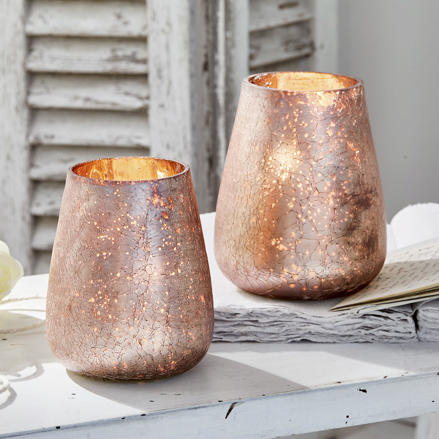 Windlicht set van 2 Chanut Twee decoratieve koperen glazen windlichten met barstpatroon op een witte tafel