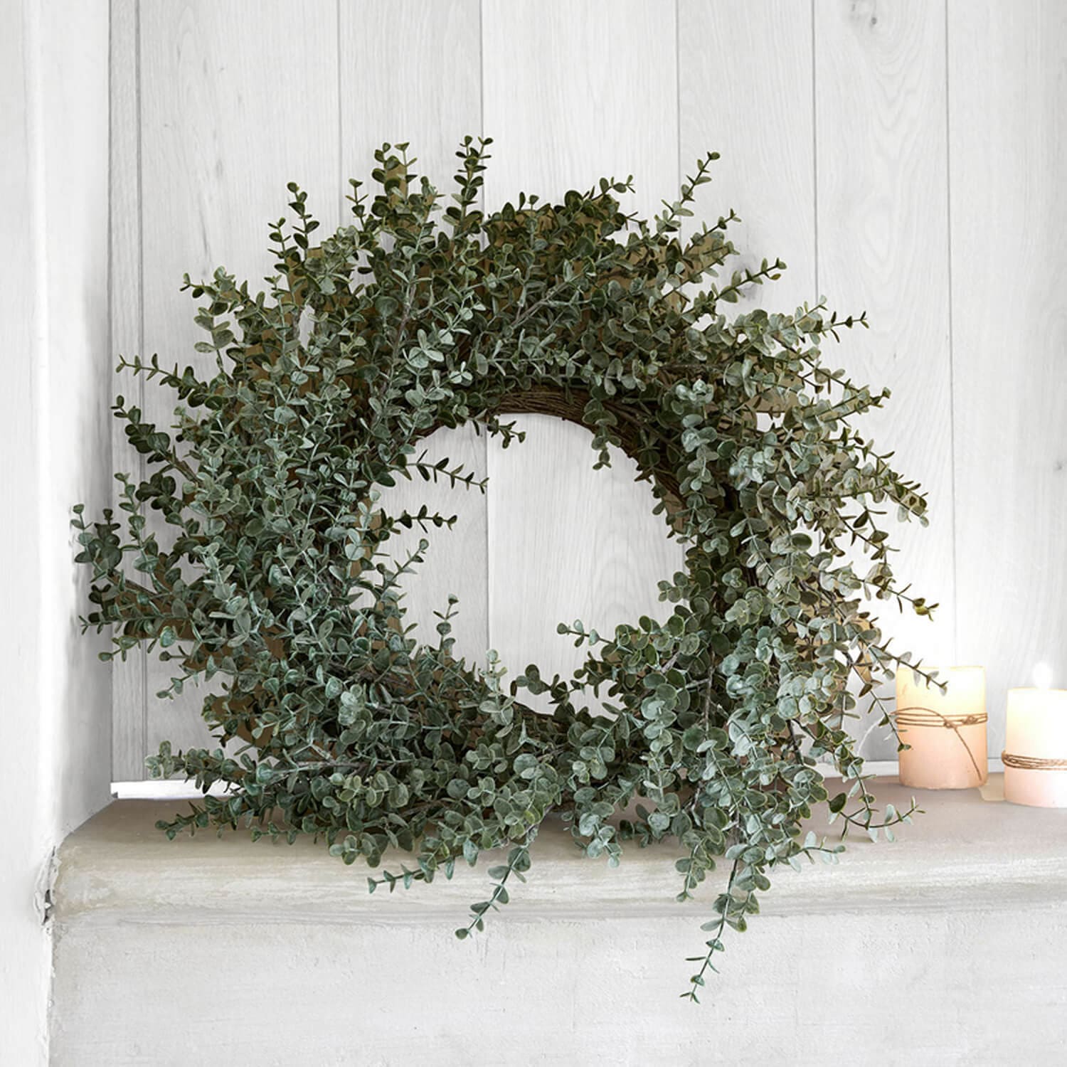 Decoratieve krans van groene eucalyptusbladeren op lichte achtergrond, natuurlijke woondecoratie