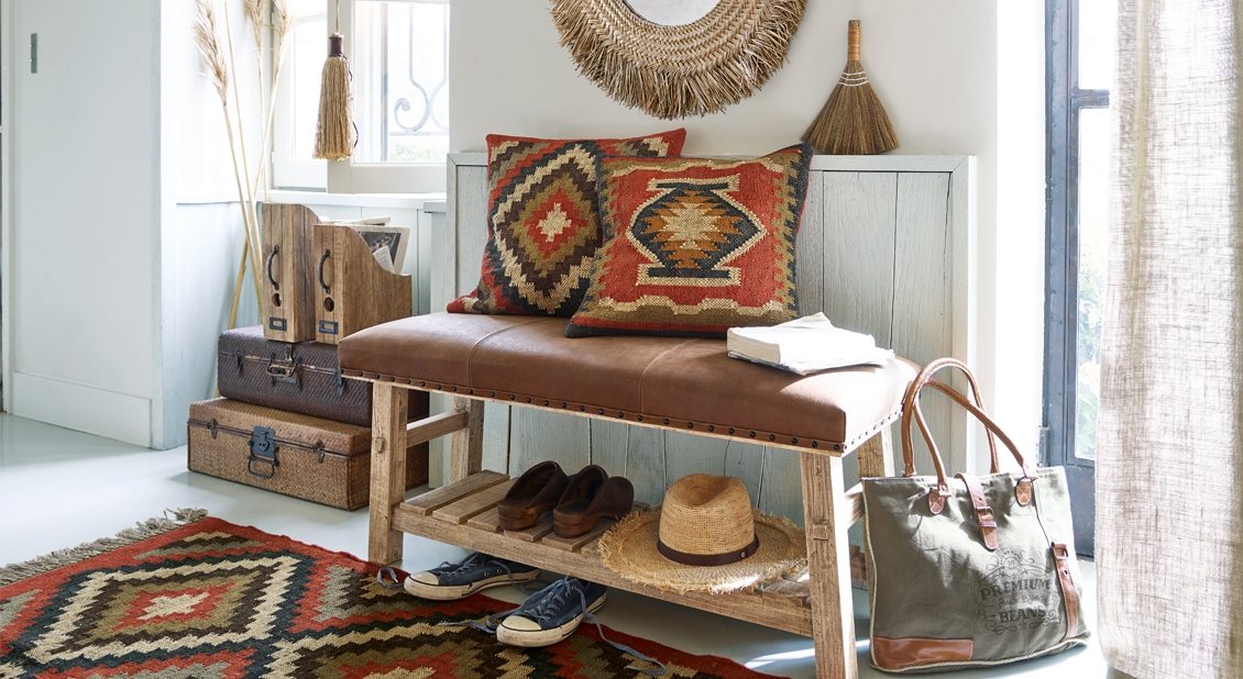 Houten bank met bruin leren kussen en twee decoratieve kussens met geometrisch boho-patroon