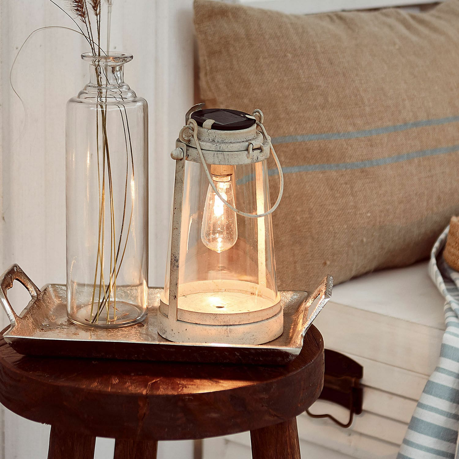 Lantaarn op zonne-energie Chénens Witte metalen lantaarn met helder glas en gloeilamp op houten kruk met decoratie