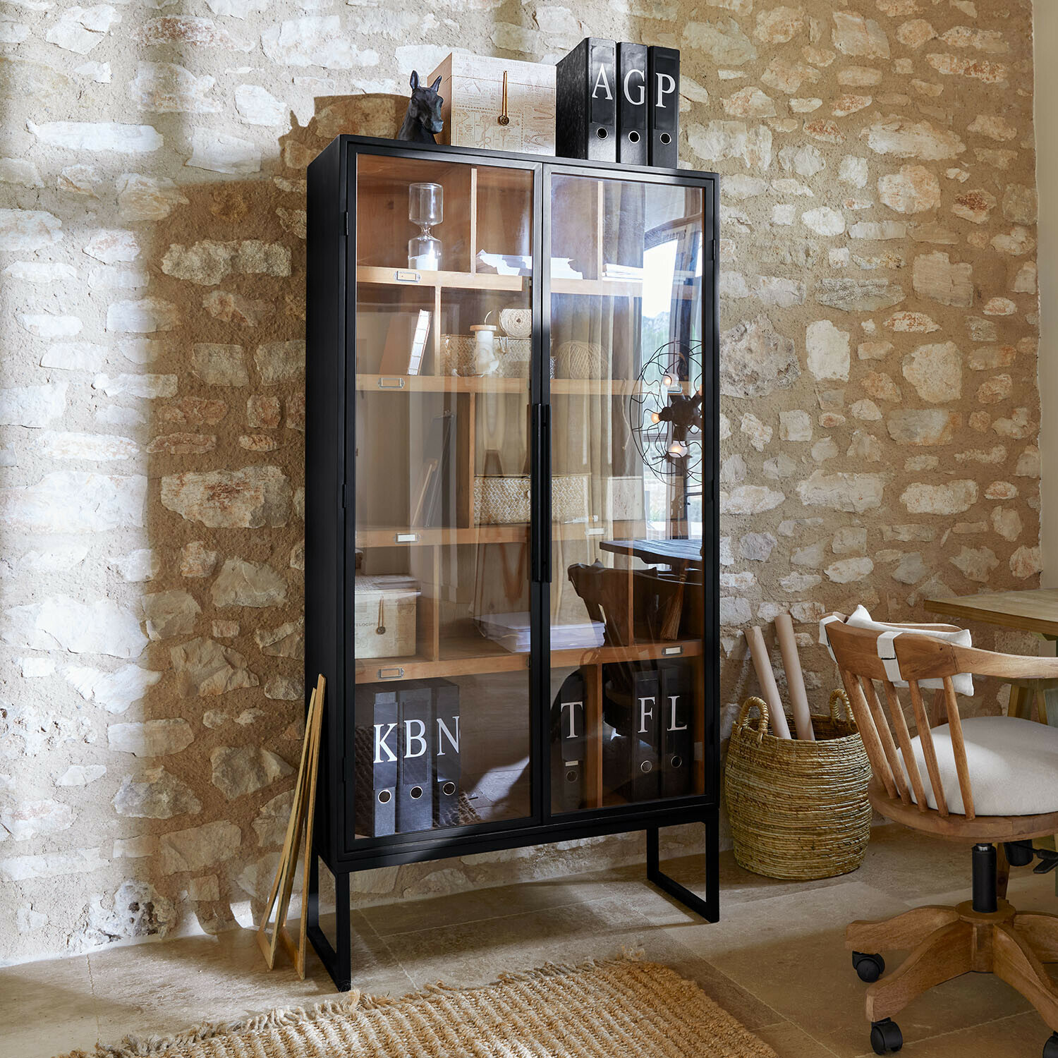 Zwarte metalen vitrinekast met glazen deuren en houten planken in rustiek kantoorinterieur