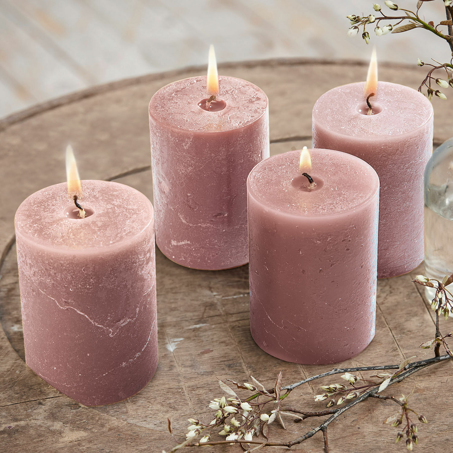 Kaars set van 4 Virrans Set van vier roze kaarsen van was op houten tafel met bloemendecoratie