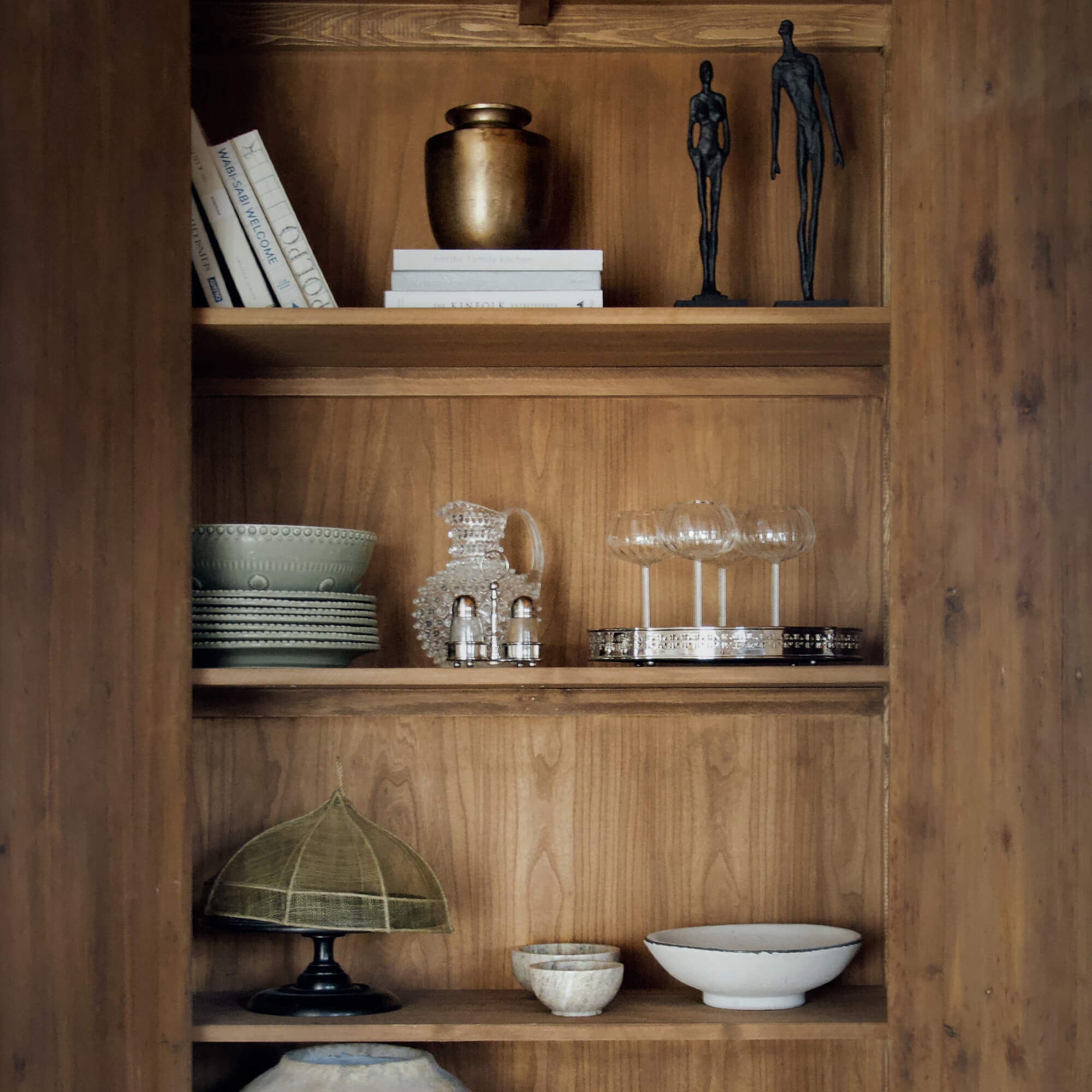 Houten plank met decoratieve items: keramiek, glas en metalen figuren voor interieur