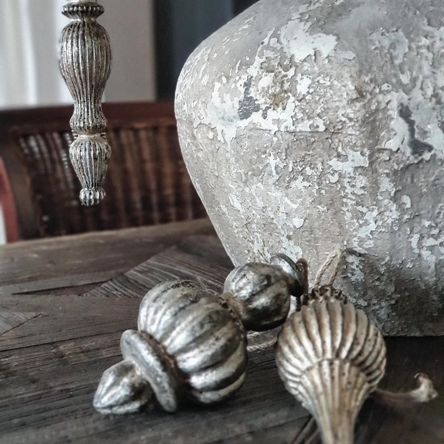 Zilverkleurige metalen decoraties op houten tafel naast een verouderde keramische vaas