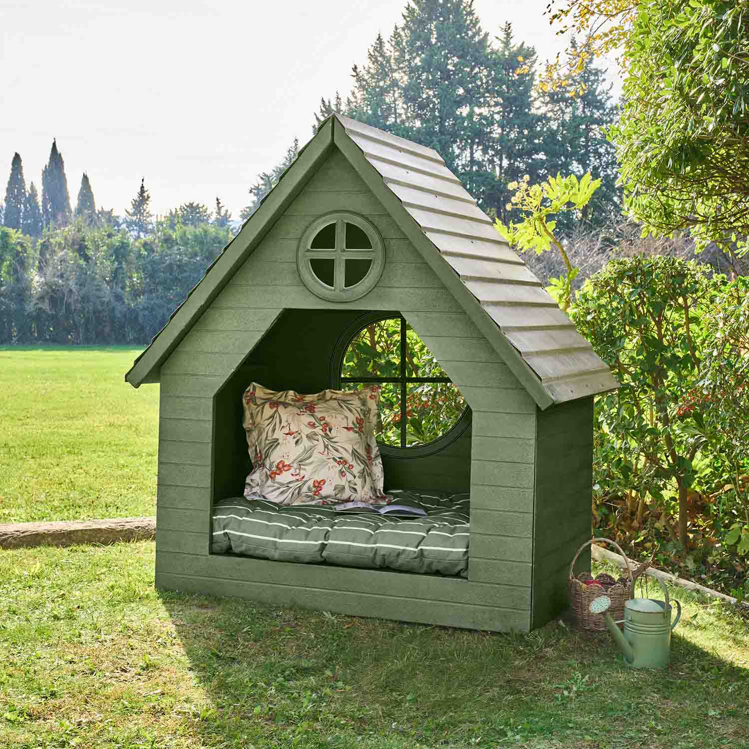 Groen houten tuinhuisje met kussen en rond raam, ideaal om buiten te ontspannen