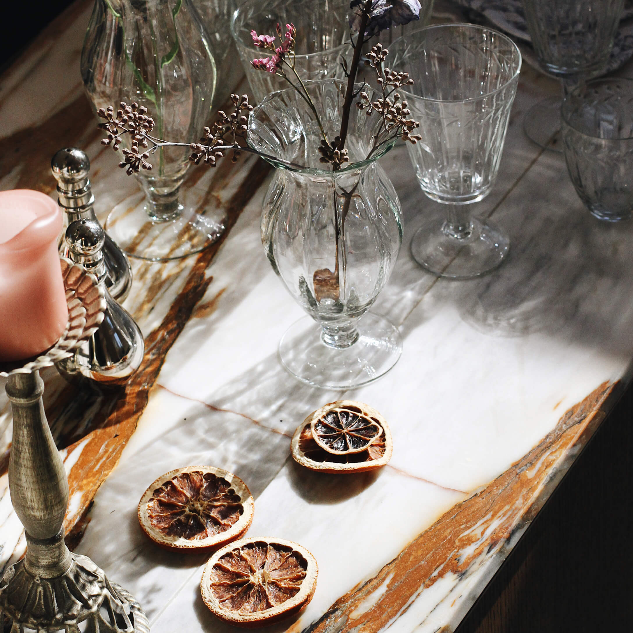 Glazen vaas met gedroogde bloemen op marmeren blad met decoratieve gedroogde fruitplakjes