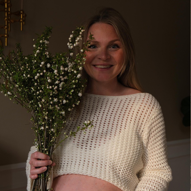 Vrouw in witte gehaakte trui met takken met witte bloemen, natuurlijke woondecoratie