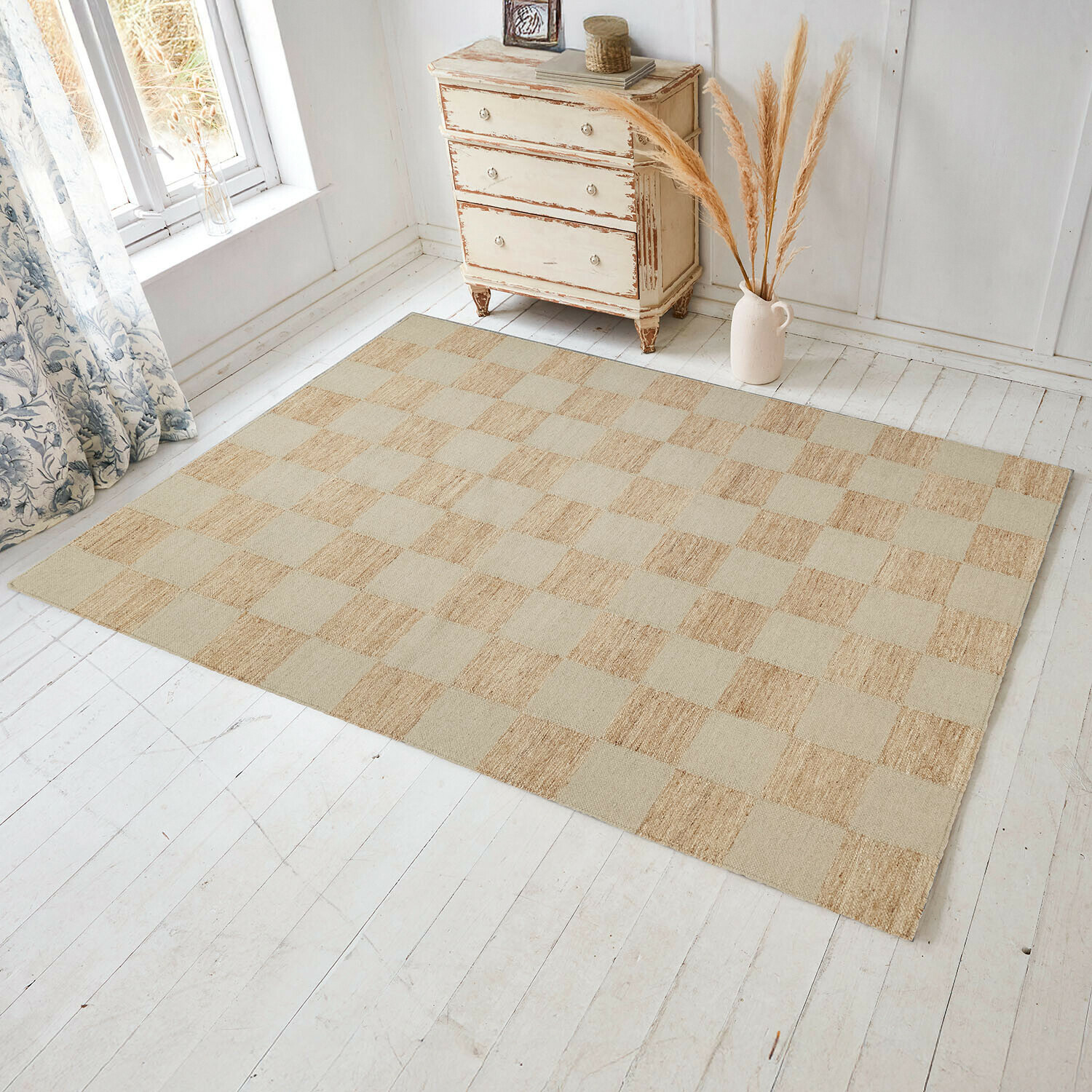 Beige geruite vloerkleed van natuurlijk materiaal op lichte houten vloer in lichte kamer