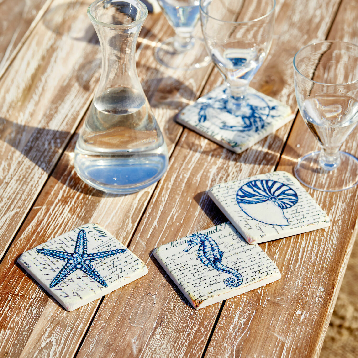 Onderzetter set van 4 Faune Marine Keramische onderzetters met blauwe zee-motieven op houten tafel, stijlvolle tafeldecoratie